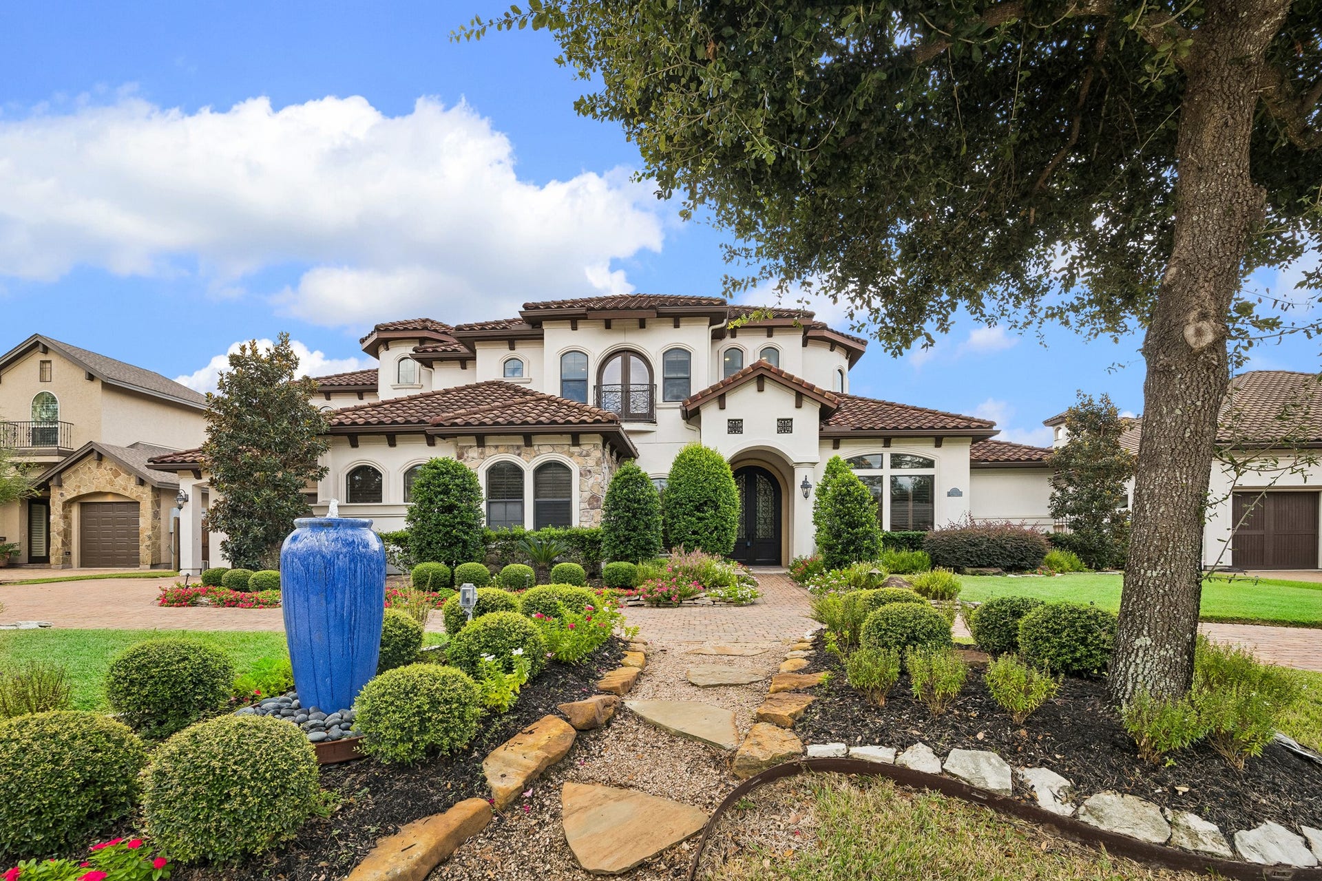 8111 Marshall Falls Drive, Spring, TX 77379 Stunning Mediterranean-style home with a classic tile roof, beautifully manicured landscaping, and a spacious driveway leading to a three-car garage.