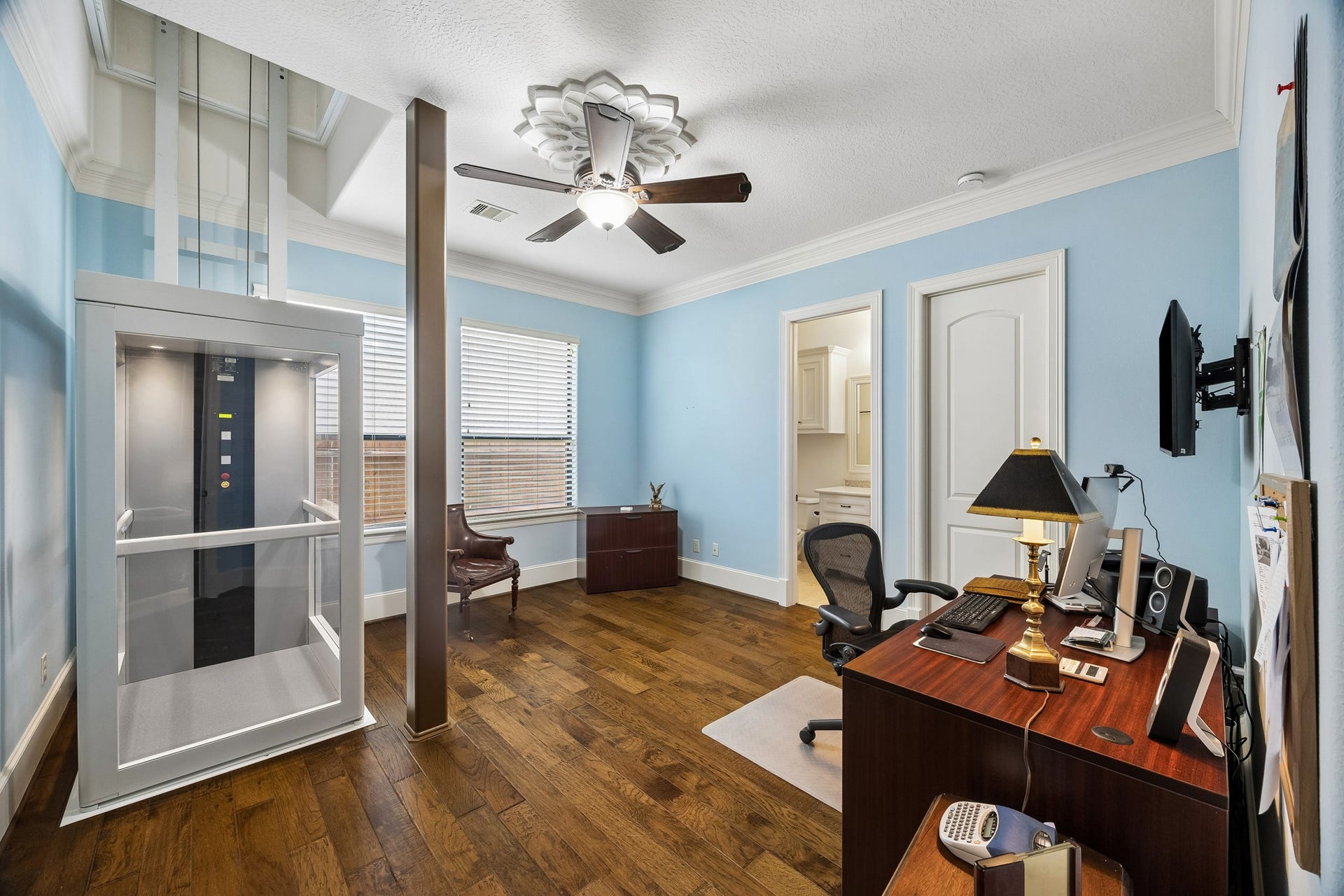 8111 Marshall Falls Drive, Spring, TX 77379 Bright and spacious first floor bedroom with en-suite bathroom features elegant wooden flooring, featuring a modern elevator for easy access, abundant natural light from large windows, and convenient built-in storage.