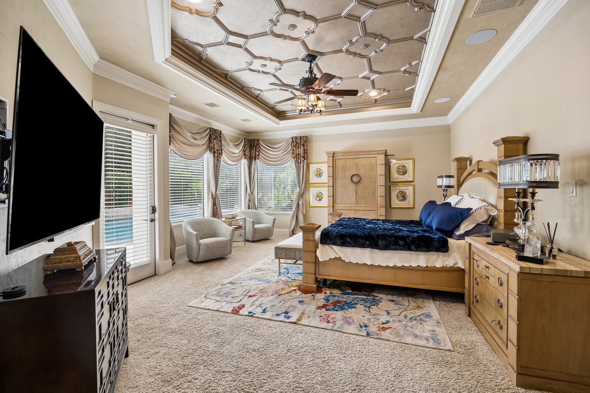 8111 Marshall Falls Drive, Spring, TX 77379 Luxurious primary bedroom featuring a stunning coffered ceiling, sitting area, and large windows offering ample natural light and pool views.