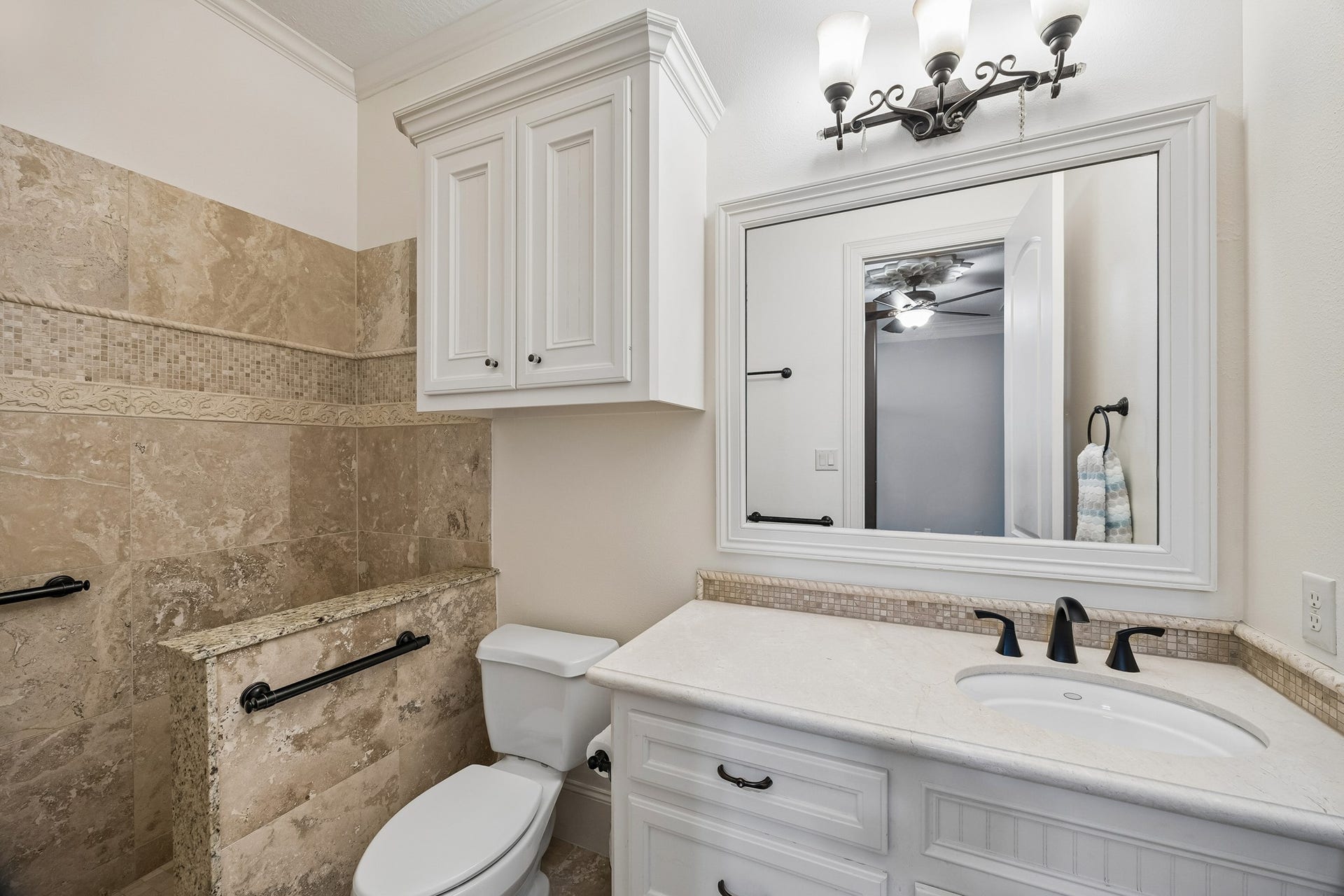 8111 Marshall Falls Drive, Spring, TX 77379 Elegant en-suite bathroom featuring a granite-tiled shower, sleek white cabinetry, and a stylish vanity with a large framed mirror.