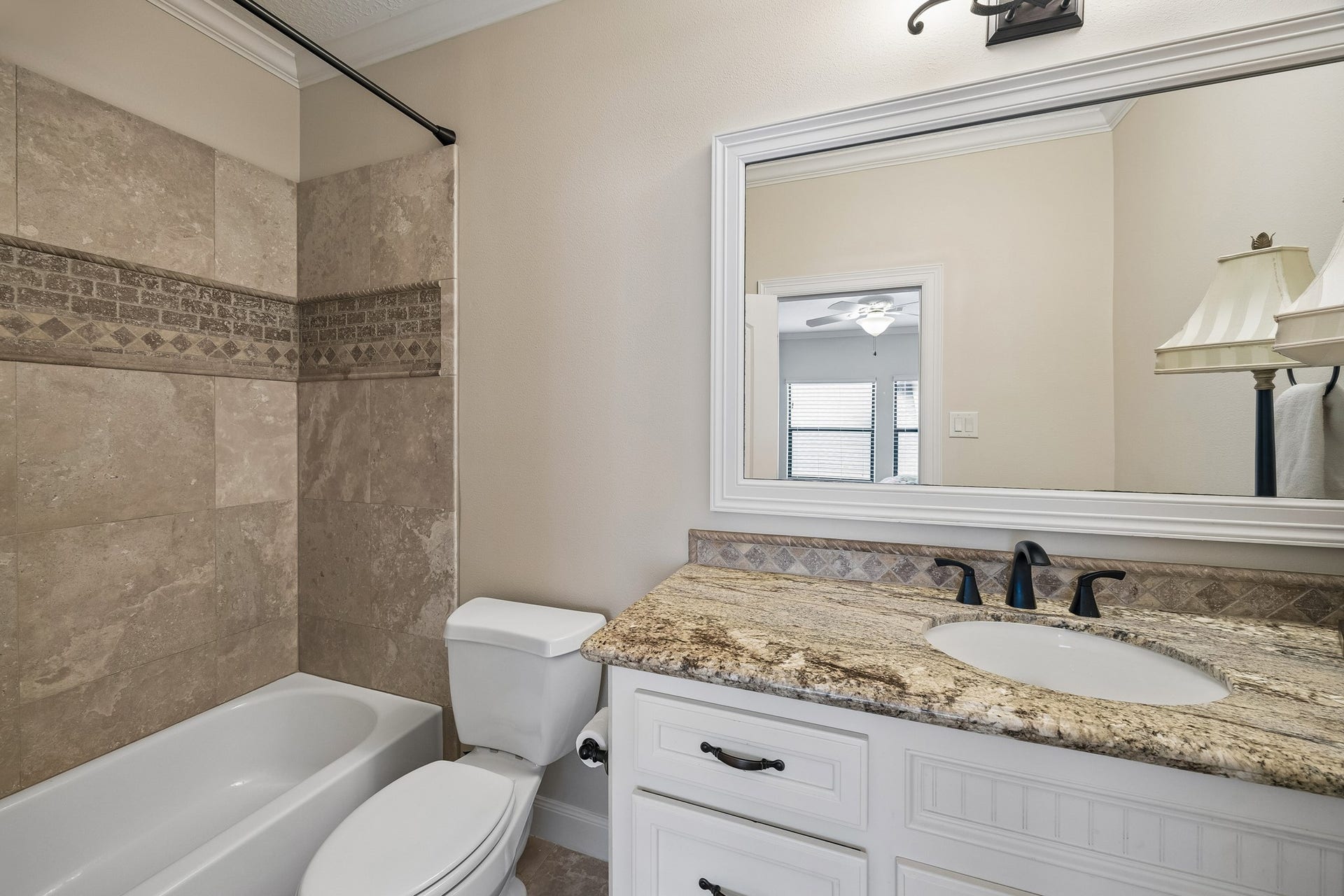 8111 Marshall Falls Drive, Spring, TX 77379 Elegant en-suite bathroom featuring a granite countertop, modern fixtures, and a stylishly tiled shower and bath area.