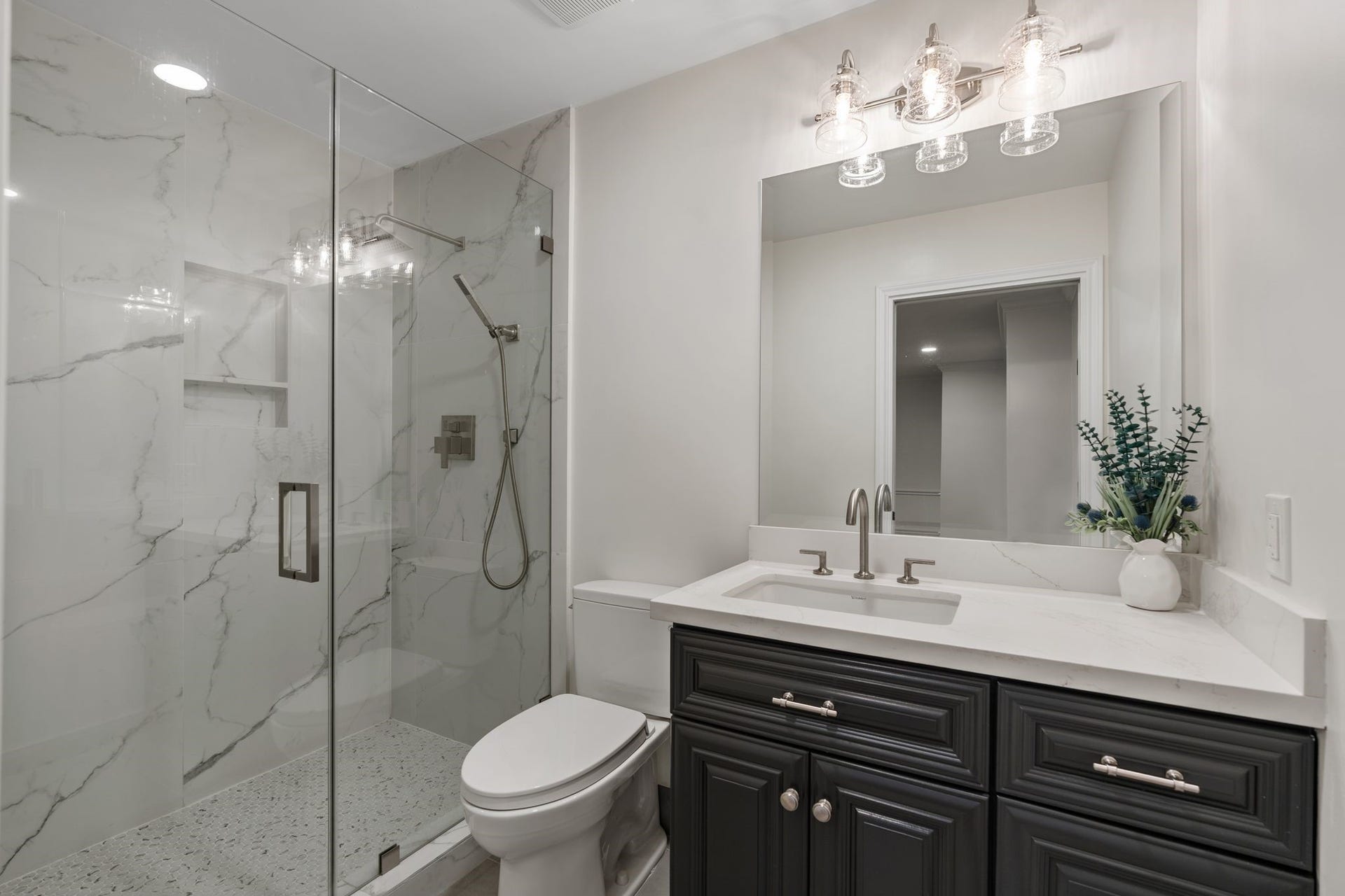 11407 Holidan Way, Hedwig Village, TX 77024 Beautifully updated en suite bath created for Secondary Bedroom #4 in 2025. Quartz-topped vanity provides storage, while the separate shower features a frameless glass door & decorative tile flooring and surround.