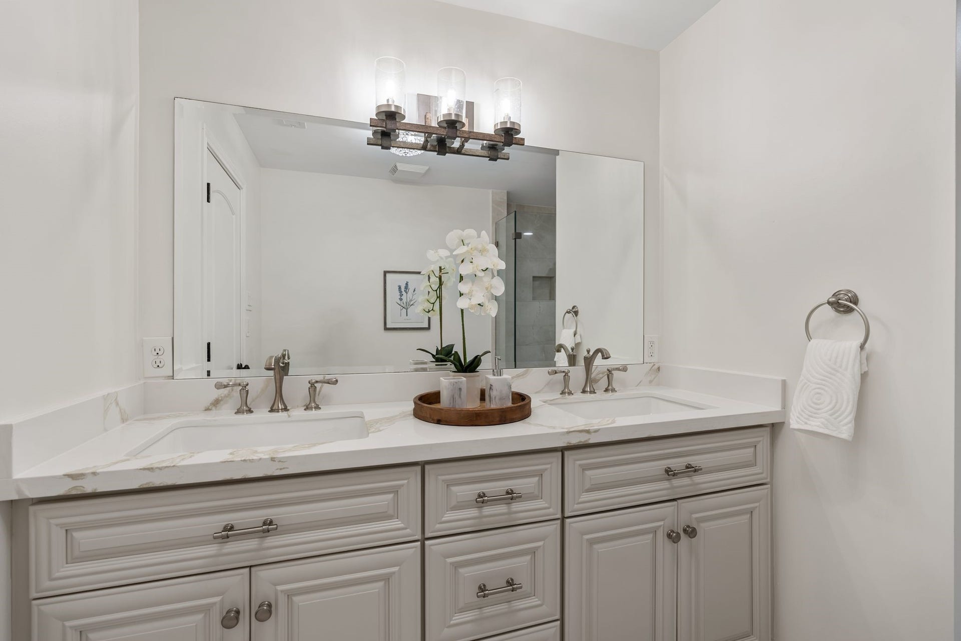 11407 Holidan Way, Hedwig Village, TX 77024 Generously sized secondary bath conveniently accessible from both the secondary bedroom#3 & game room hallway. Updated vanity features dual sinks, quartz countertop, soft-close cabinetry & built-in mirror, complemented by a frameless glass shower w/ decorative tile & separate oversized jetted tub.