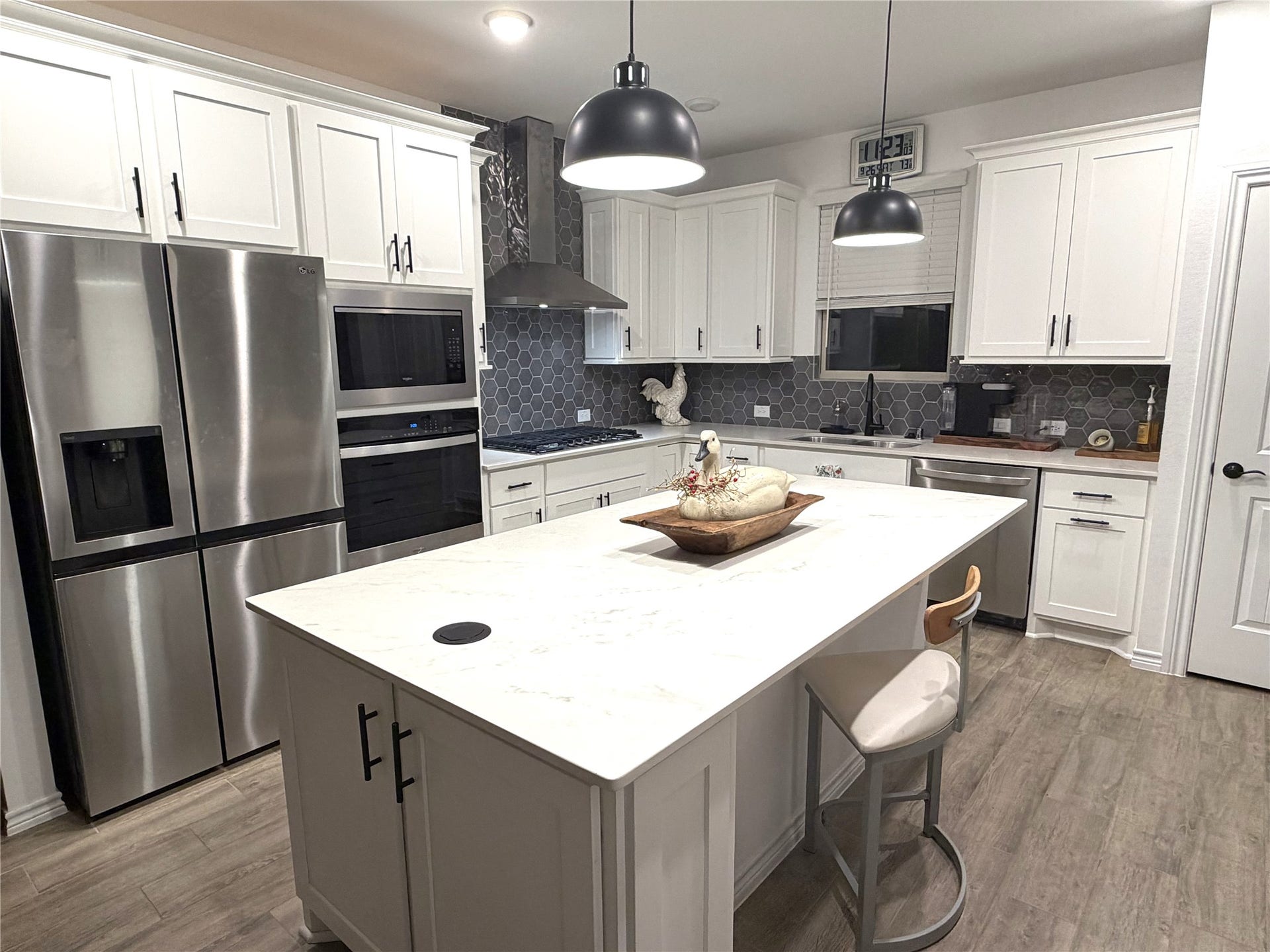8015 Prospect Drive, Fulshear, TX 77441 Designed for both beauty and function, this kitchen features quartz countertops, stainless steel appliances, and soft-close cabinetry. The spacious island includes a convenient pop-up electrical outlet, offering a clever modern touch for cooking, entertaining, and everyday convenience.