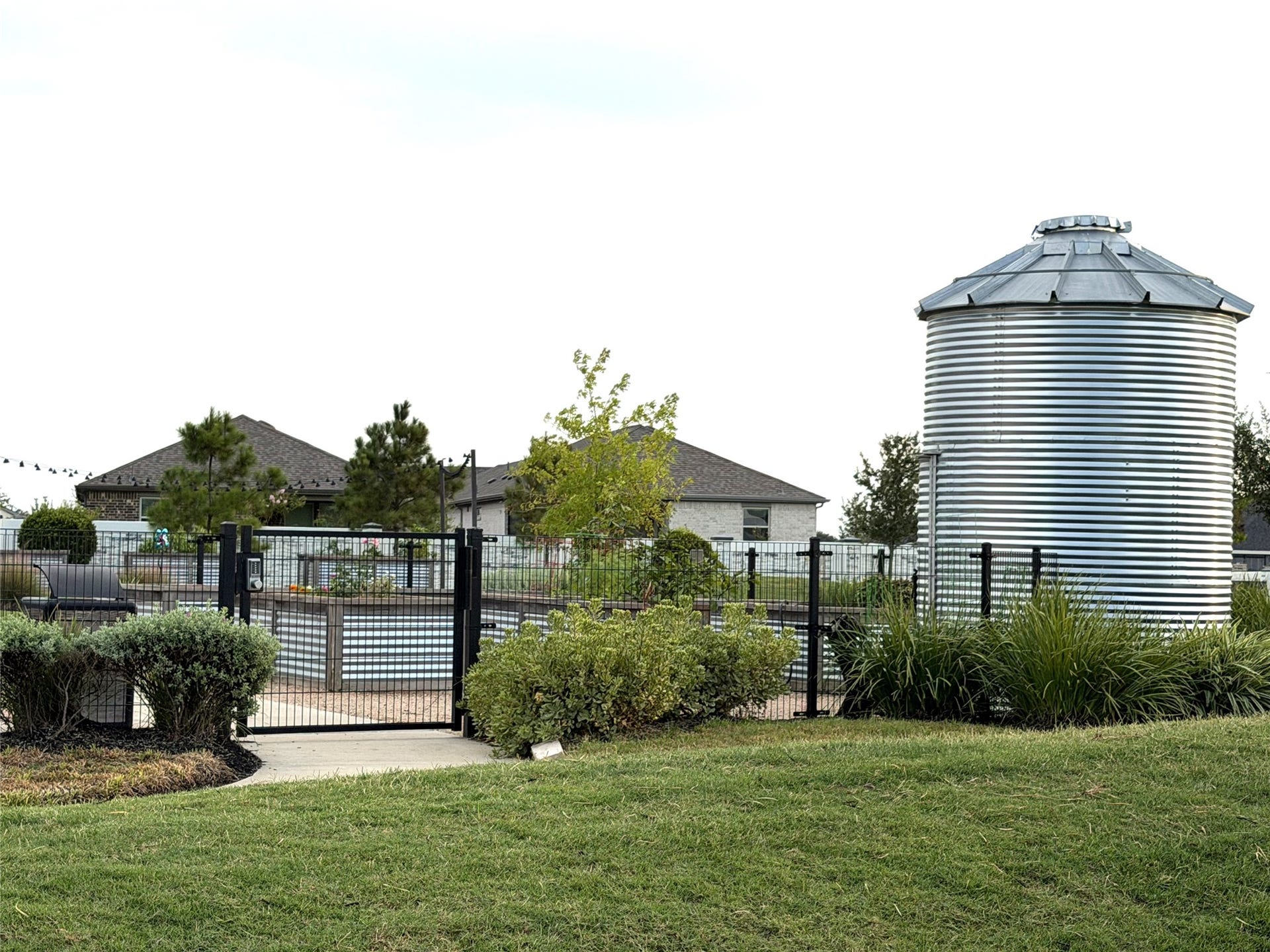 8015 Prospect Drive, Fulshear, TX 77441 Explore the gated garden area, featuring landscaped greenery and a distinctive silo-inspired structure. A charming outdoor setting that adds character to Del Webb Fulshear's community amenities.