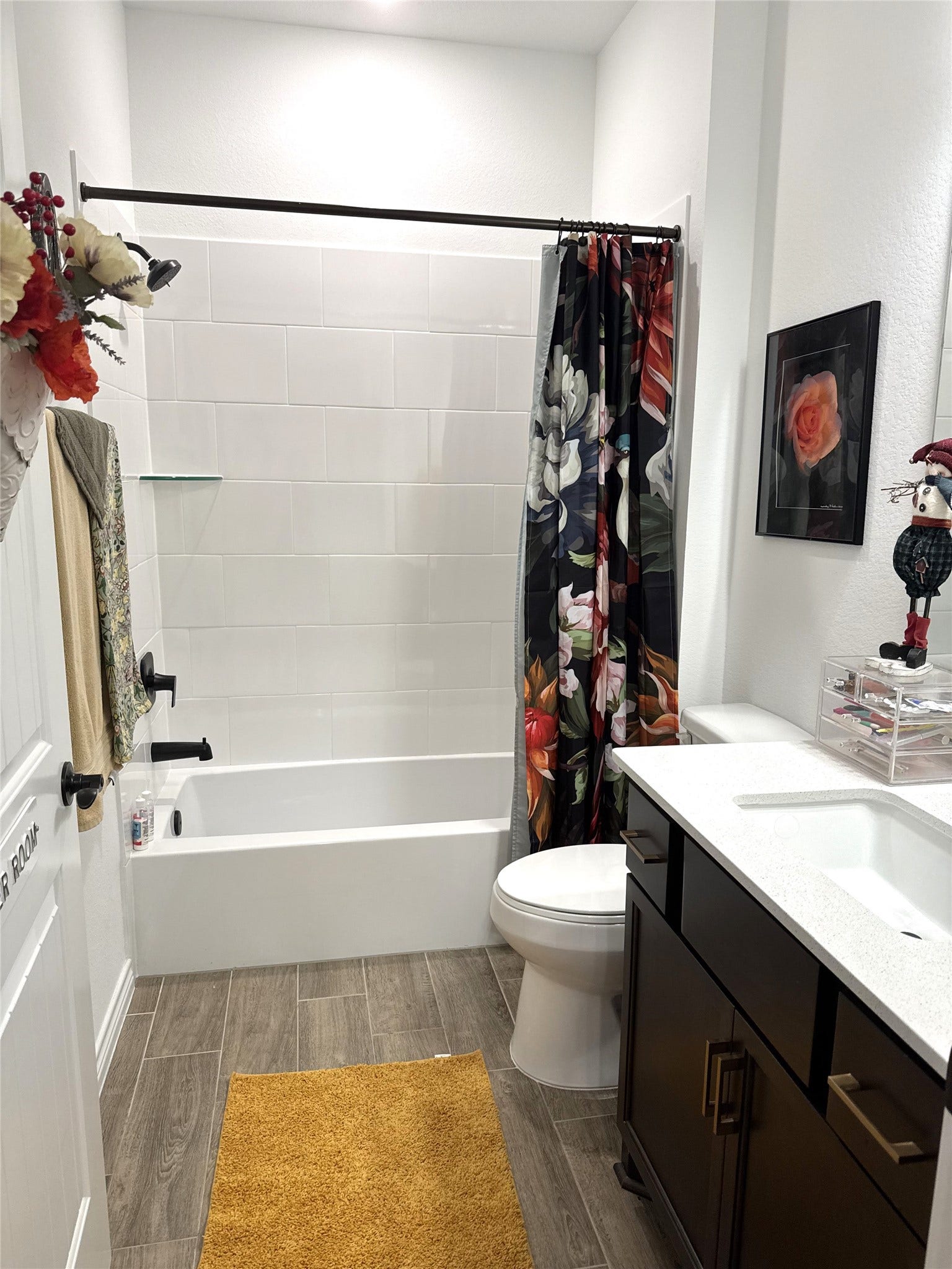 8015 Prospect Drive, Fulshear, TX 77441 Stylish secondary bathroom features a full tub and shower combination with crisp white tile. A sleek dark vanity and modern fixtures add a touch of sophistication.