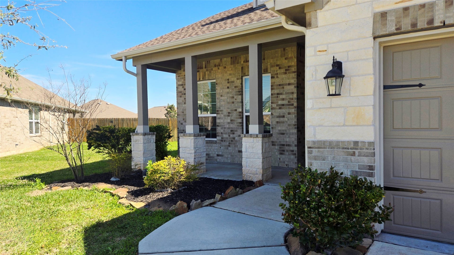 3210 Star Jasmine Lane, Richmond, TX 77406 Inviting covered front porch with brick and stone exterior, decorative columns, manicured landscaping, and a curved walkway leading to the front entry.
