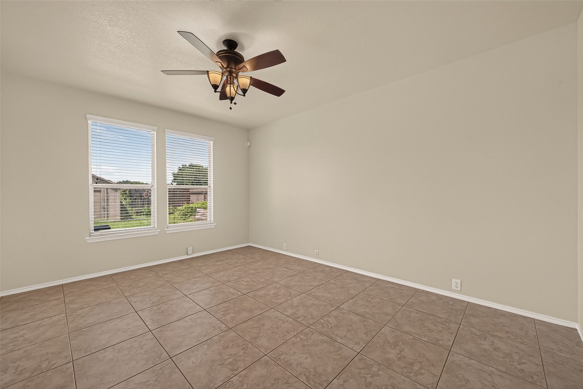 26130 Ripley Hills Drive, Richmond, TX 77406 This room features neutral walls, tile flooring, and a ceiling fan with lights. Two large windows provide natural light and a view of the outdoors, creating a bright and airy space.