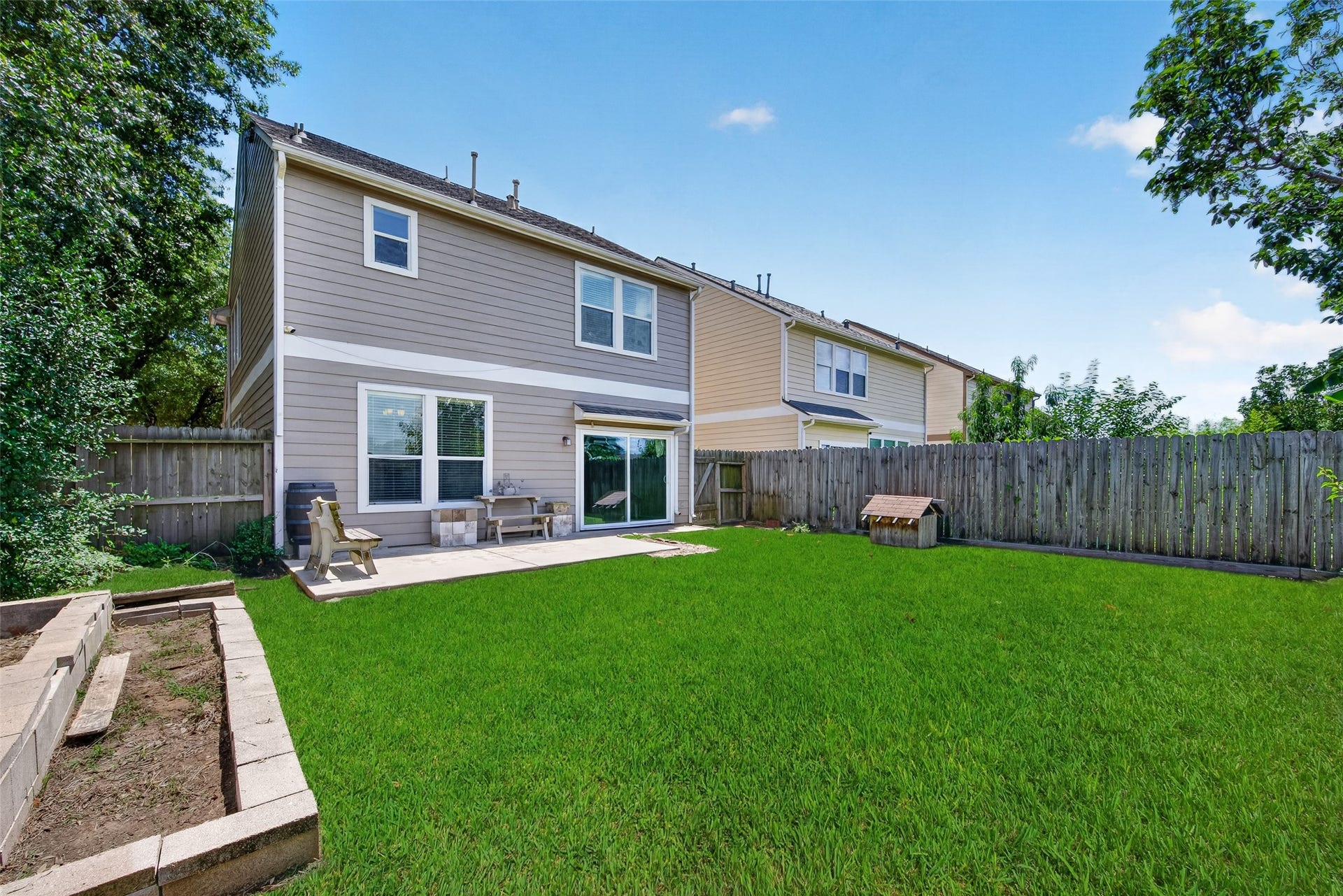 26130 Ripley Hills Drive, Richmond, TX 77406 Spacious backyard with a well-maintained lawn, patio area with seating, and a wooden fence for privacy. Ideal for outdoor activities and relaxation.