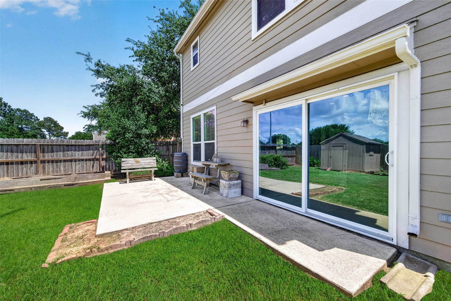 26130 Ripley Hills Drive, Richmond, TX 77406 Spacious backyard with lush green lawn, a small shed, and a concrete patio area perfect for outdoor seating. Ideal for relaxation and gardening.