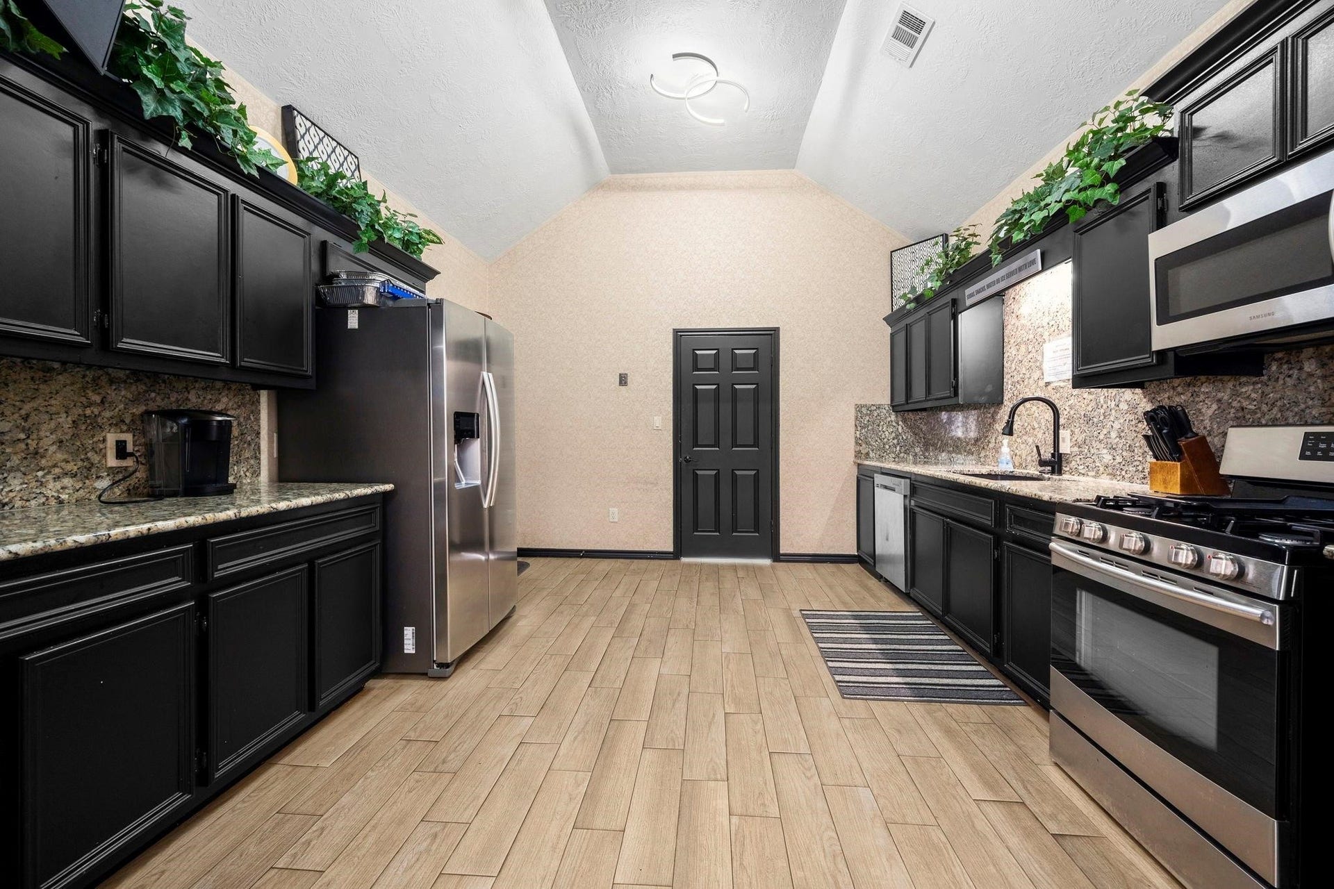 This kitchen features modern stainless-steel appliances, dark cabinetry, granite countertops, and a herringbone-patterned tile floor. It has a neutral color palette and is well-lit with a combination of natural and ceiling lighting. This is the Information center's kitchen located on the property