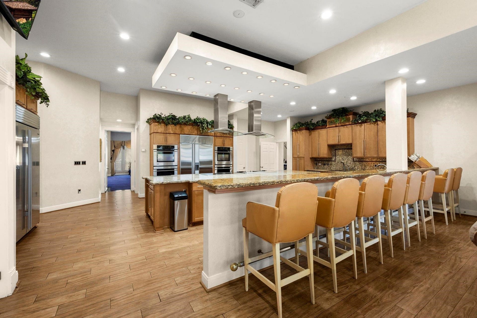This photo features a spacious modern kitchen with stainless steel appliances, ample cabinetry, a large island with seating, and sleek recessed lighting, perfect for entertaining and cooking.