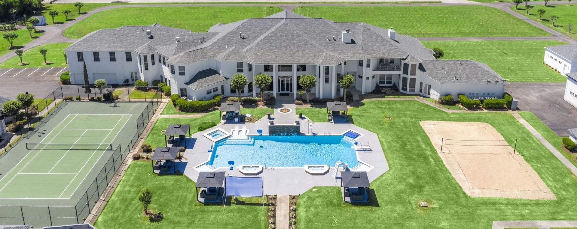 Discover an expansive luxury retreat featuring private tennis courts, a resort-style pool, and extensive grounds perfect for leisure and entertainment.
