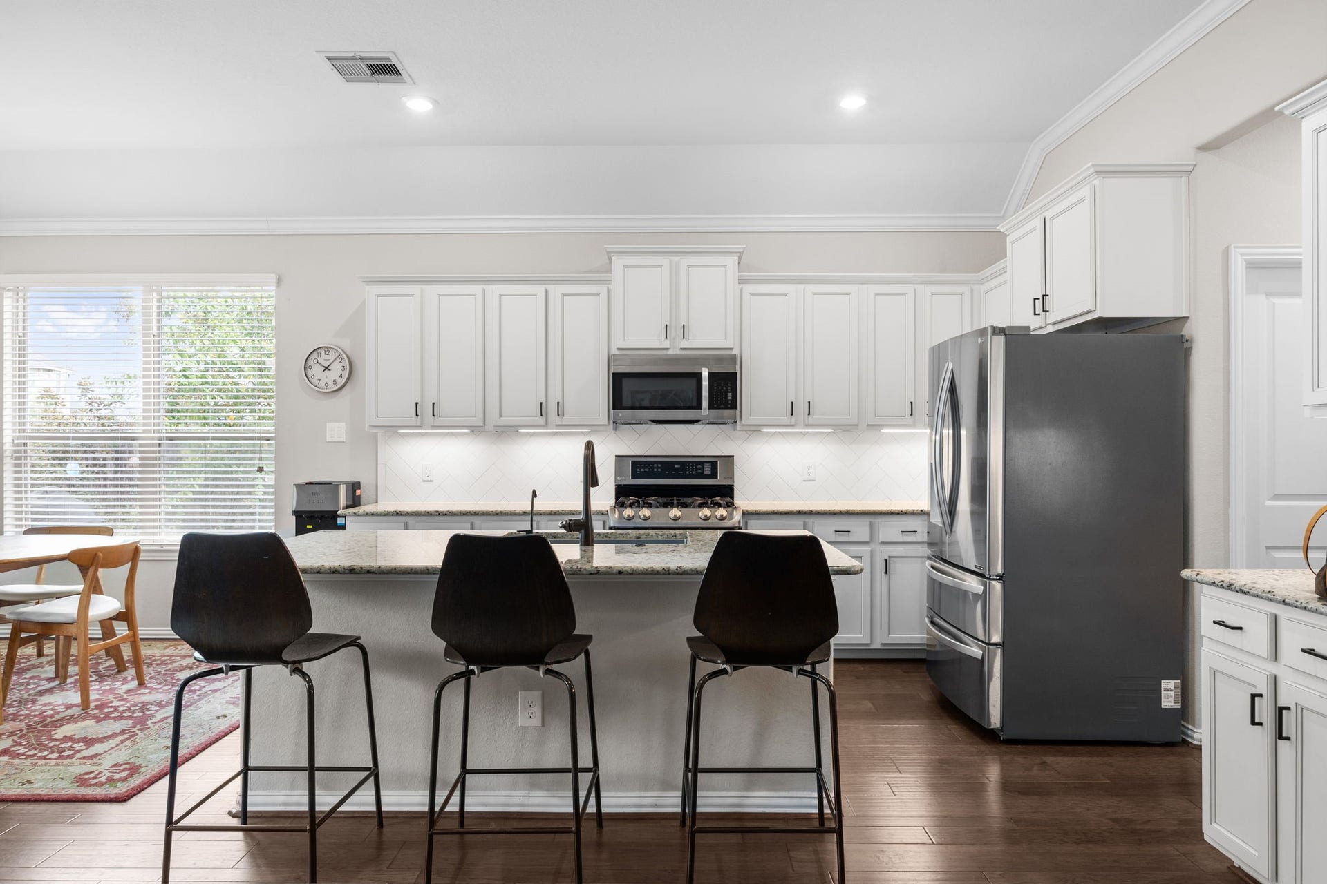 Modern kitchen with sleek stainless steel appliances, a spacious island with bar seating, and elegant white cabinetry, offering a bright and inviting space for cooking and entertaining.