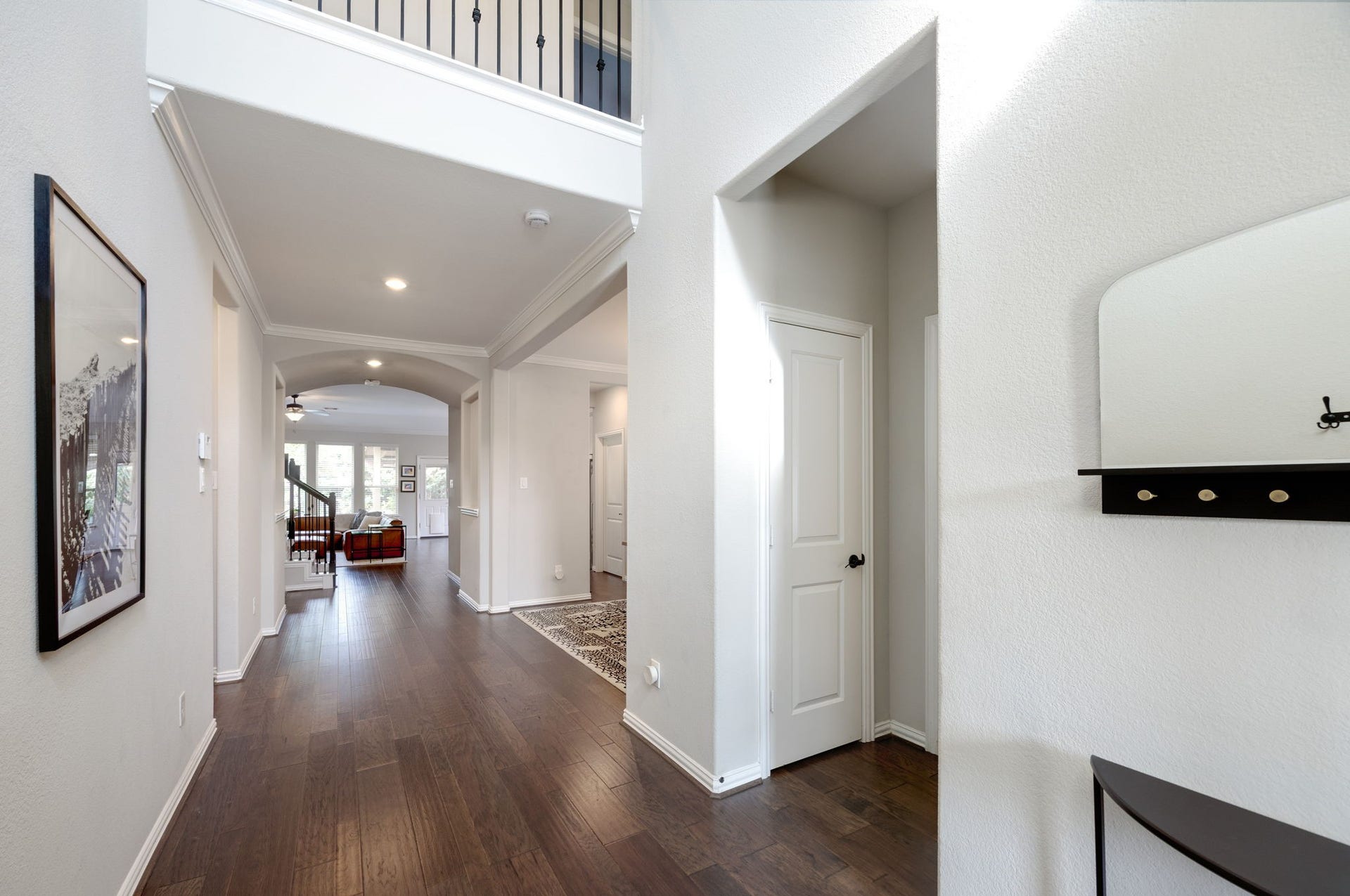 Bright and welcoming foyer with elegant hardwood floors, high ceilings, and a view leading to the spacious living area.