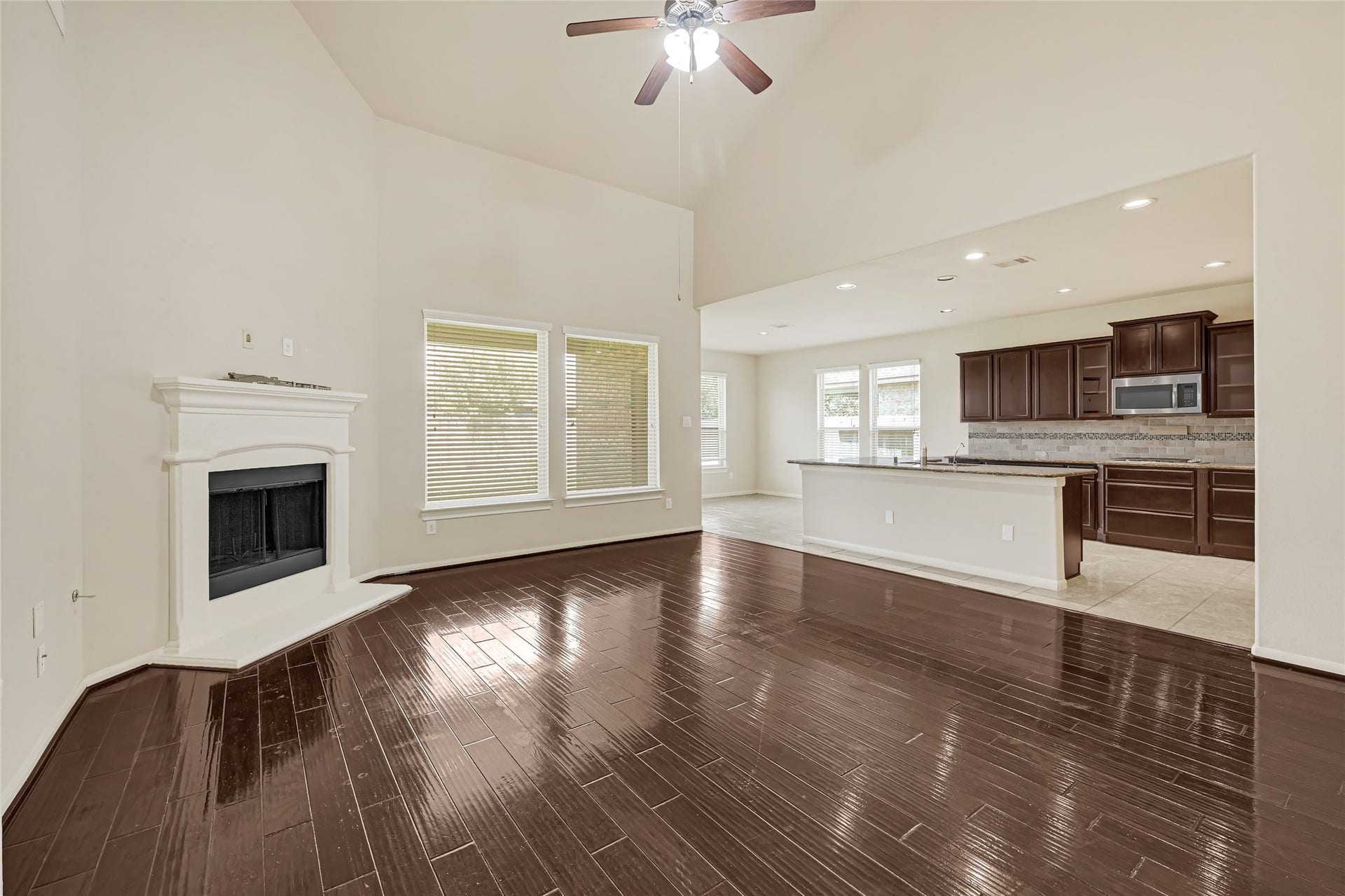 736 Somerset Landing Lane, League City, TX 77573 Spacious living room with hardwood flooring, a fireplace, ceiling fan, and views into the kitchen.