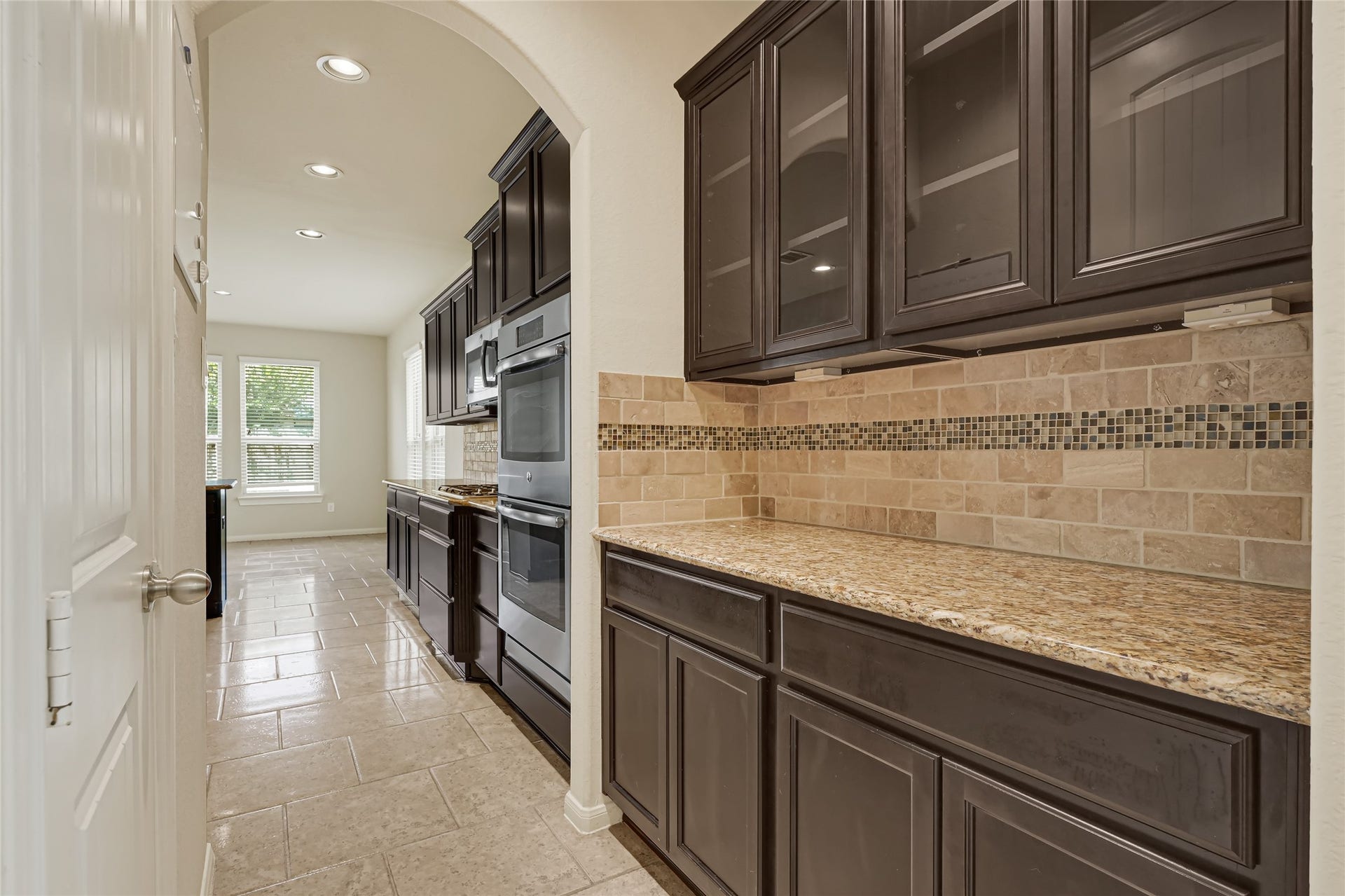 736 Somerset Landing Lane, League City, TX 77573 Long granite countertop with dark wood cabinetry, tiled backsplash, and generous storage.