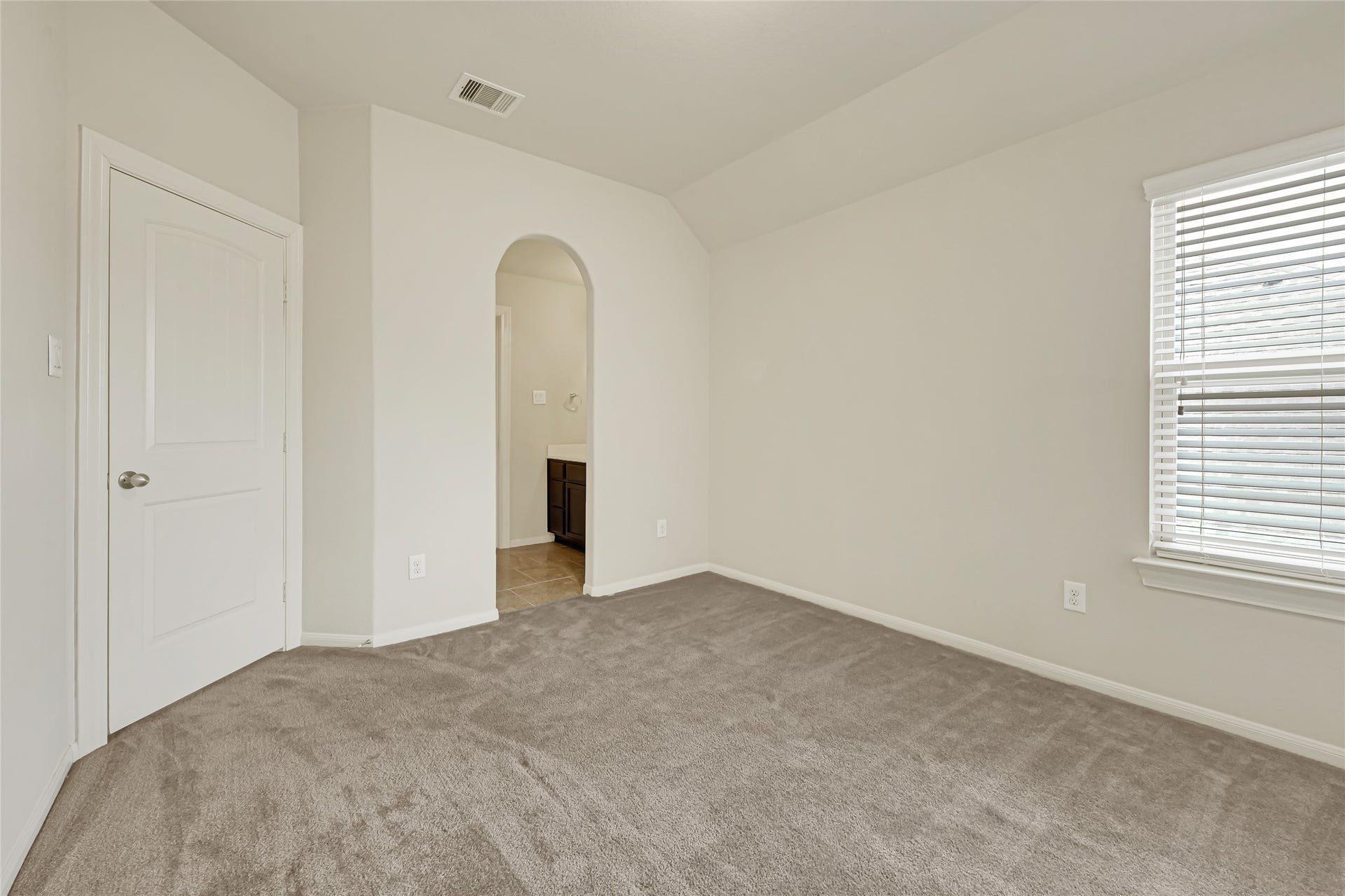 736 Somerset Landing Lane, League City, TX 77573 Comfortable bedroom with neutral carpet, natural light, and an arched doorway.