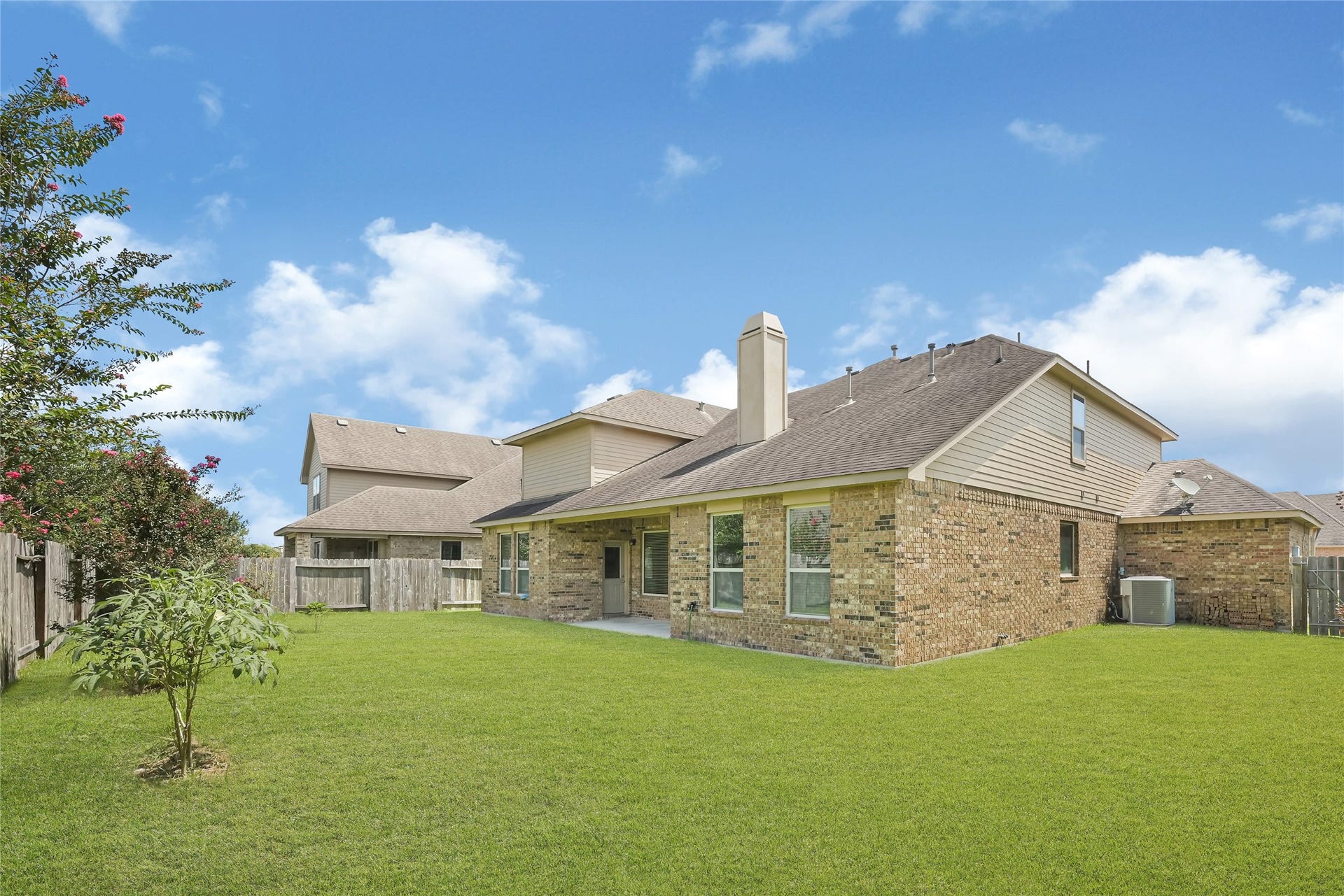 736 Somerset Landing Lane, League City, TX 77573 Wide backyard view showcasing the homes rear elevation, covered patio, and generous green space.