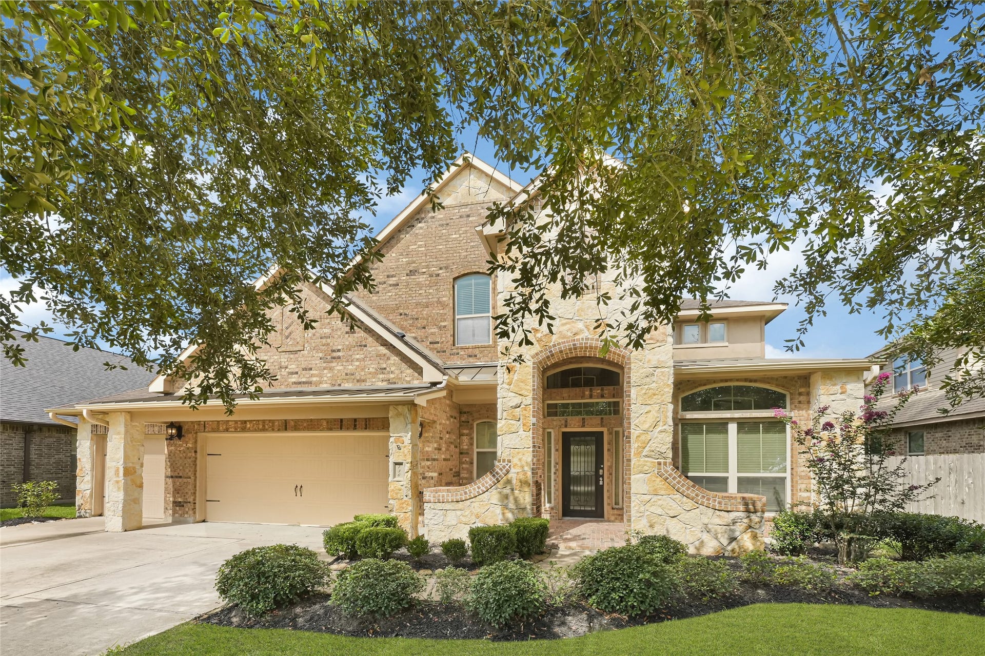 736 Somerset Landing Lane, League City, TX 77573 Impressive brick-and-stone exterior with a car garage, covered entry, arched architectural details, mature landscaping, and strong curb appeal.