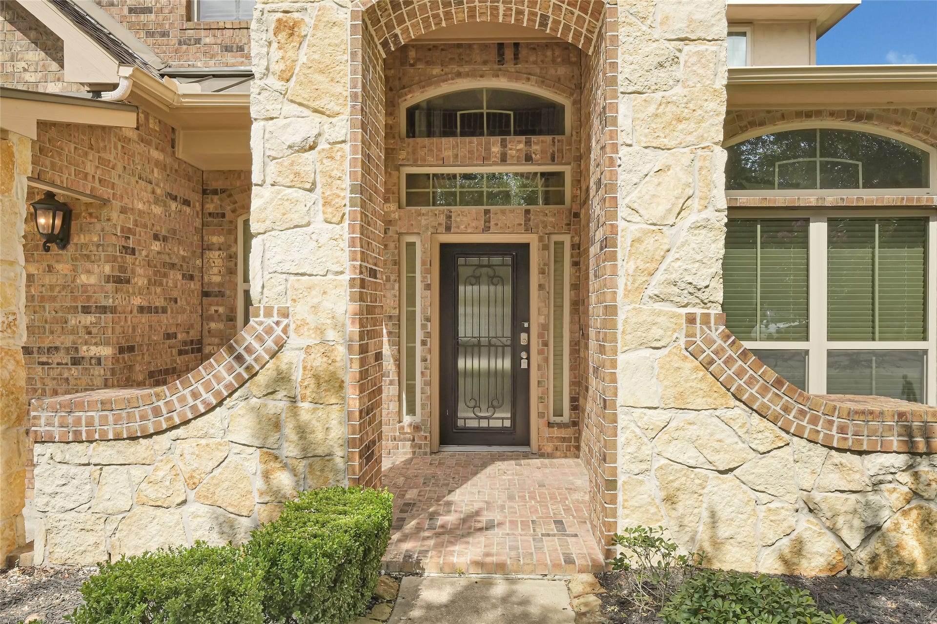 736 Somerset Landing Lane, League City, TX 77573 Covered front entry highlighted by stone accents, decorative glass doors, and arched architectural details.