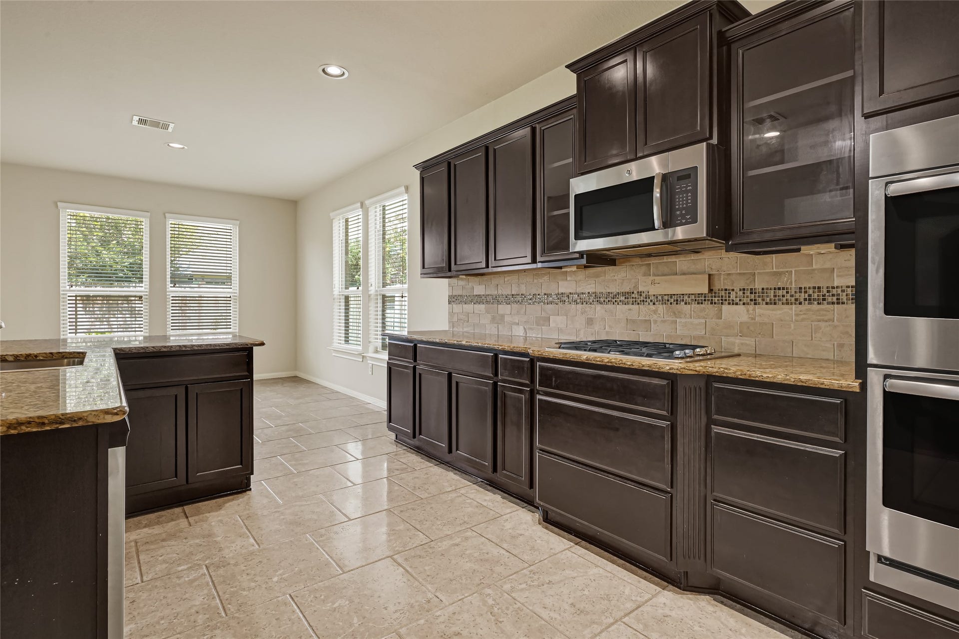 736 Somerset Landing Lane, League City, TX 77573 Spacious kitchen featuring dark cabinetry, granite countertops, tile flooring, and abundant storage.