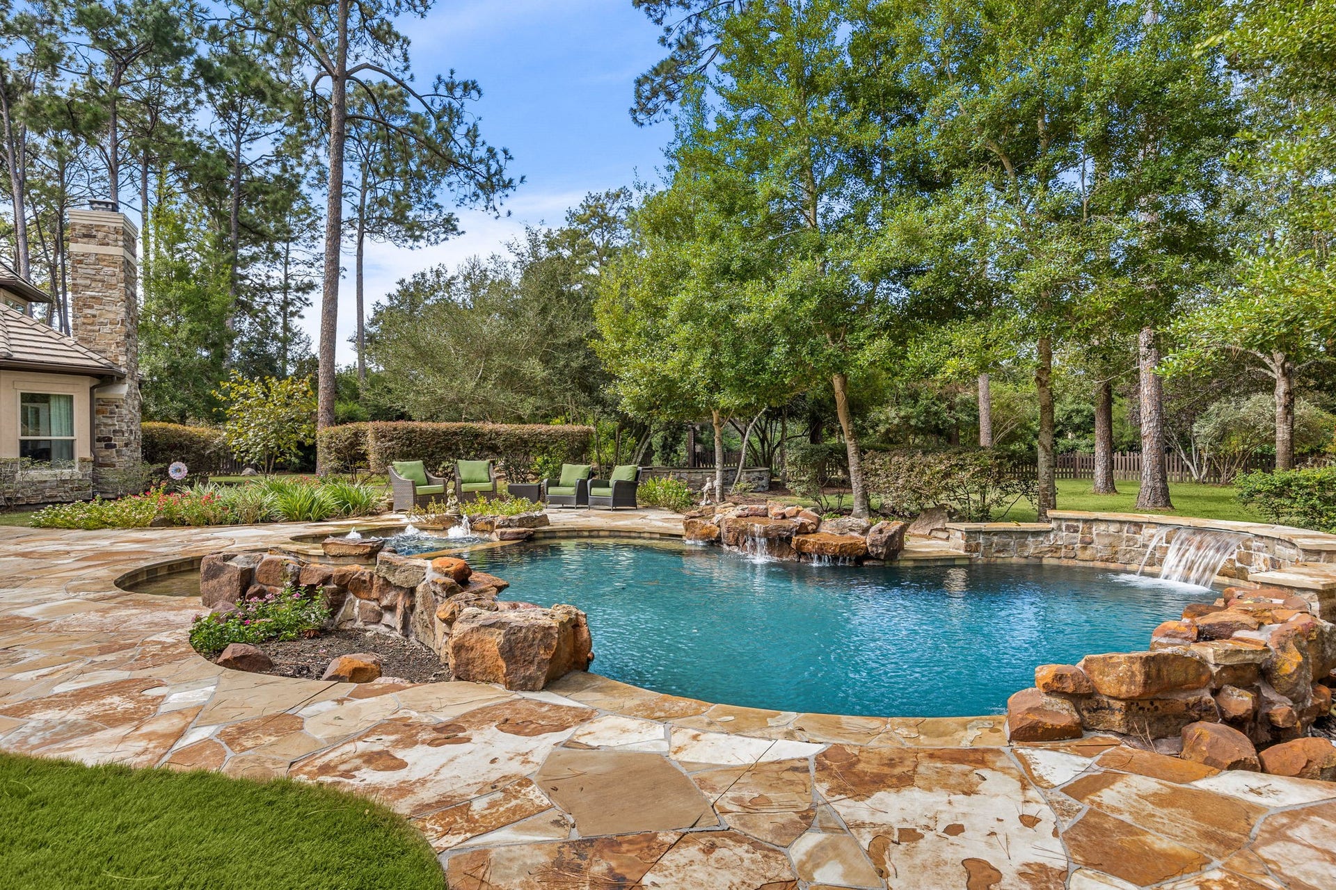 2127 Fawn Meadow Lane, Richmond, TX 77406 Resort-style backyard featuring a beautiful swimming pool and spa with tranquil water features surrounded by mature trees for privacy.