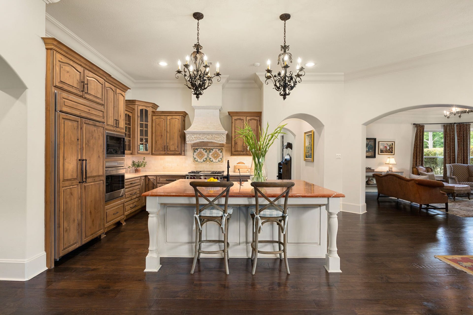 2127 Fawn Meadow Lane, Richmond, TX 77406 Spacious kitchen featuring a large center island with seating, custom cabinetry, wood paneled refrigerator, and decorative lighting.