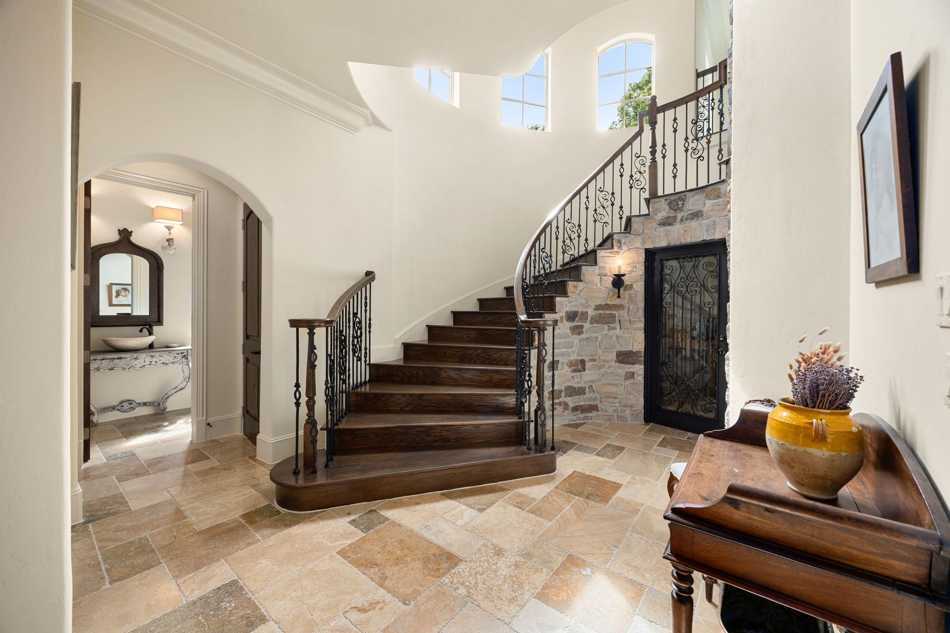 2127 Fawn Meadow Lane, Richmond, TX 77406 Grand rotunda staircase and foyer showcasing beautiful architectural details with stone wall and iron door leading to the wine cellar.