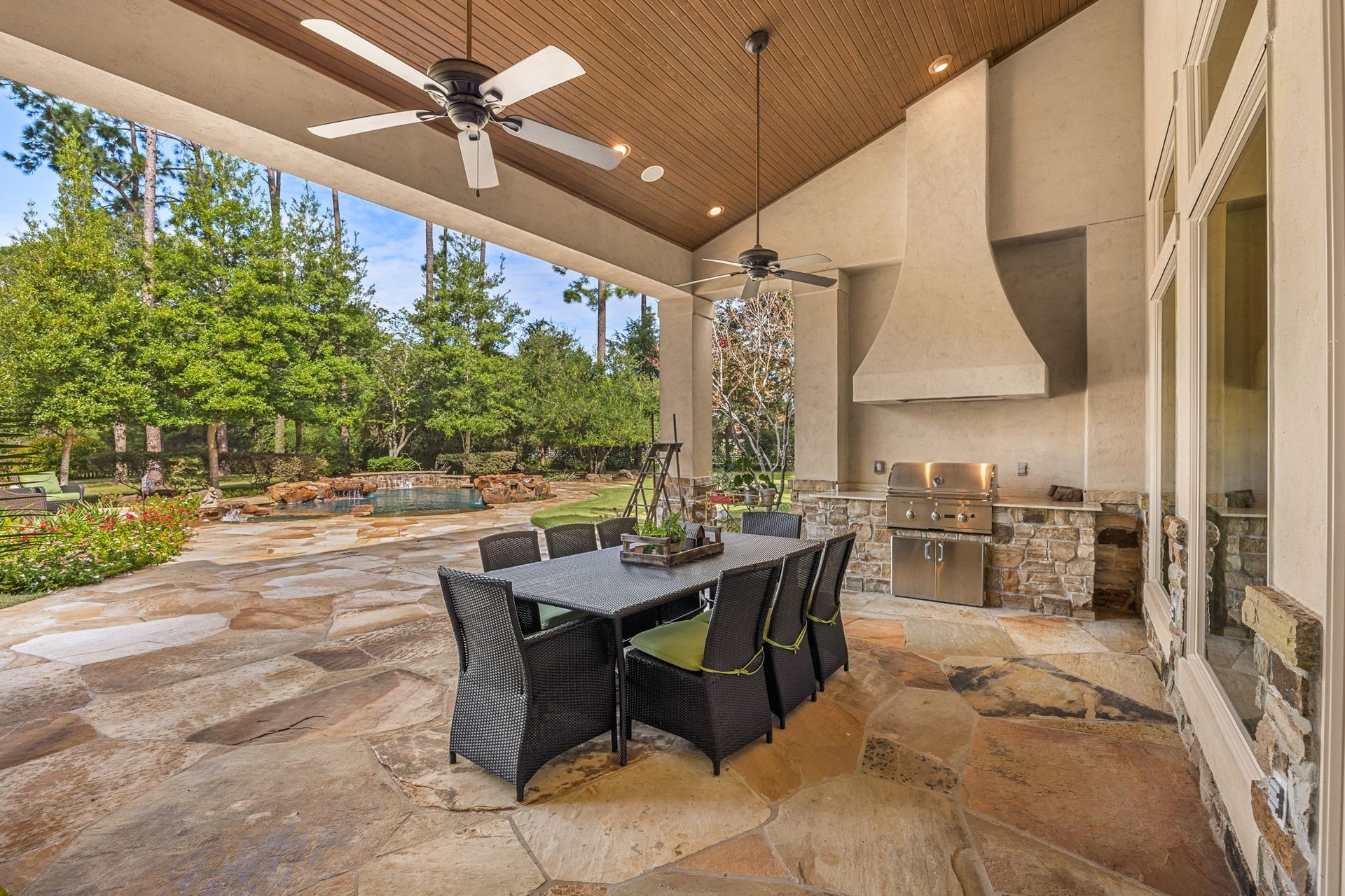 2127 Fawn Meadow Lane, Richmond, TX 77406 Covered outdoor living area featuring an outdoor kitchen with gas grill and vent hood, ceiling fan, and space for outdoor dining and entertaining.