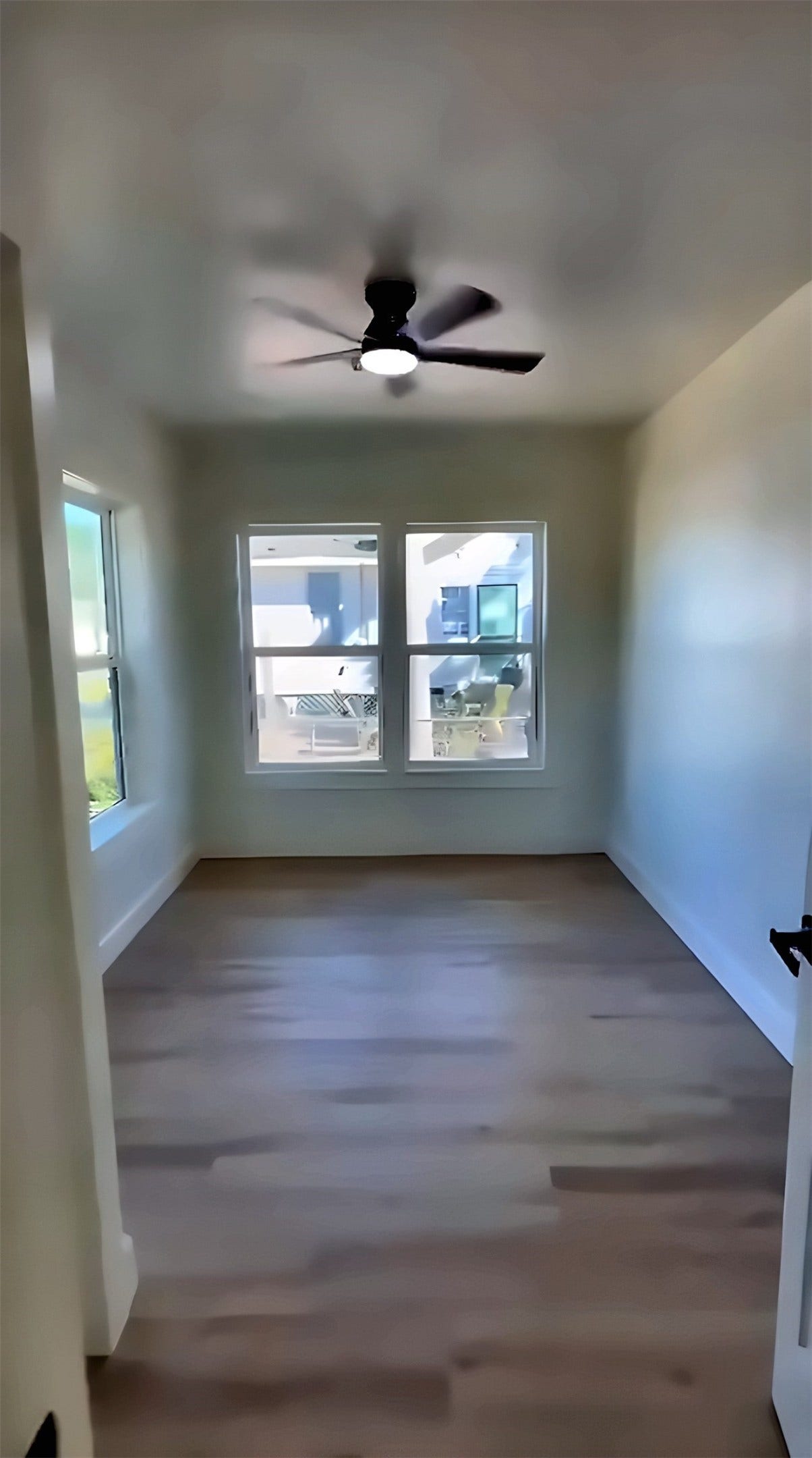 Room with large windows, ceiling fan and wood-look flooring