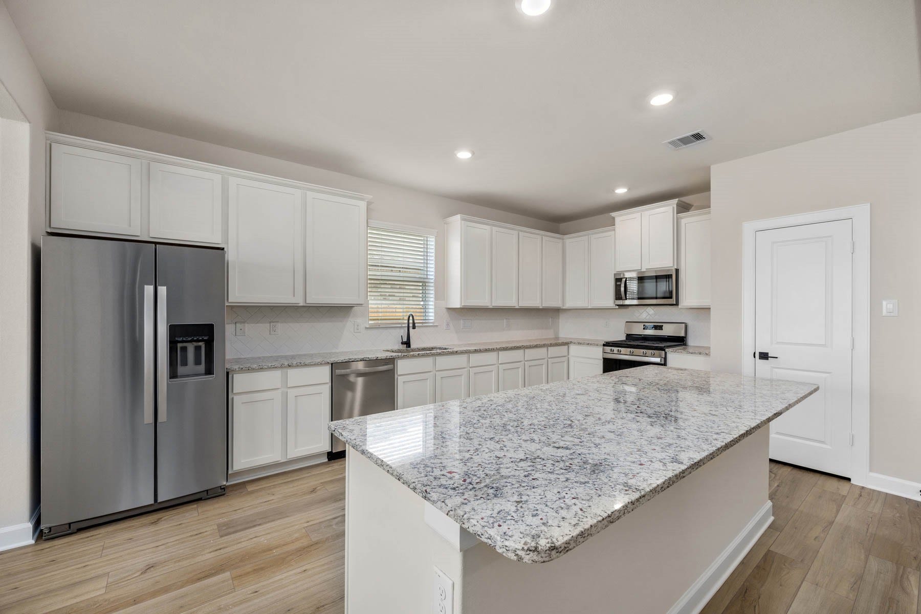 2921 Fair Wind Lane, Texas City, TX 77510 Step into this beautifully designed kitchen boasting a spacious island with a large breakfast bar overlooking the living room, a chic herringbone pattern backsplash, and modern stainless steel appliances. Perfect for entertaining and everyday living!