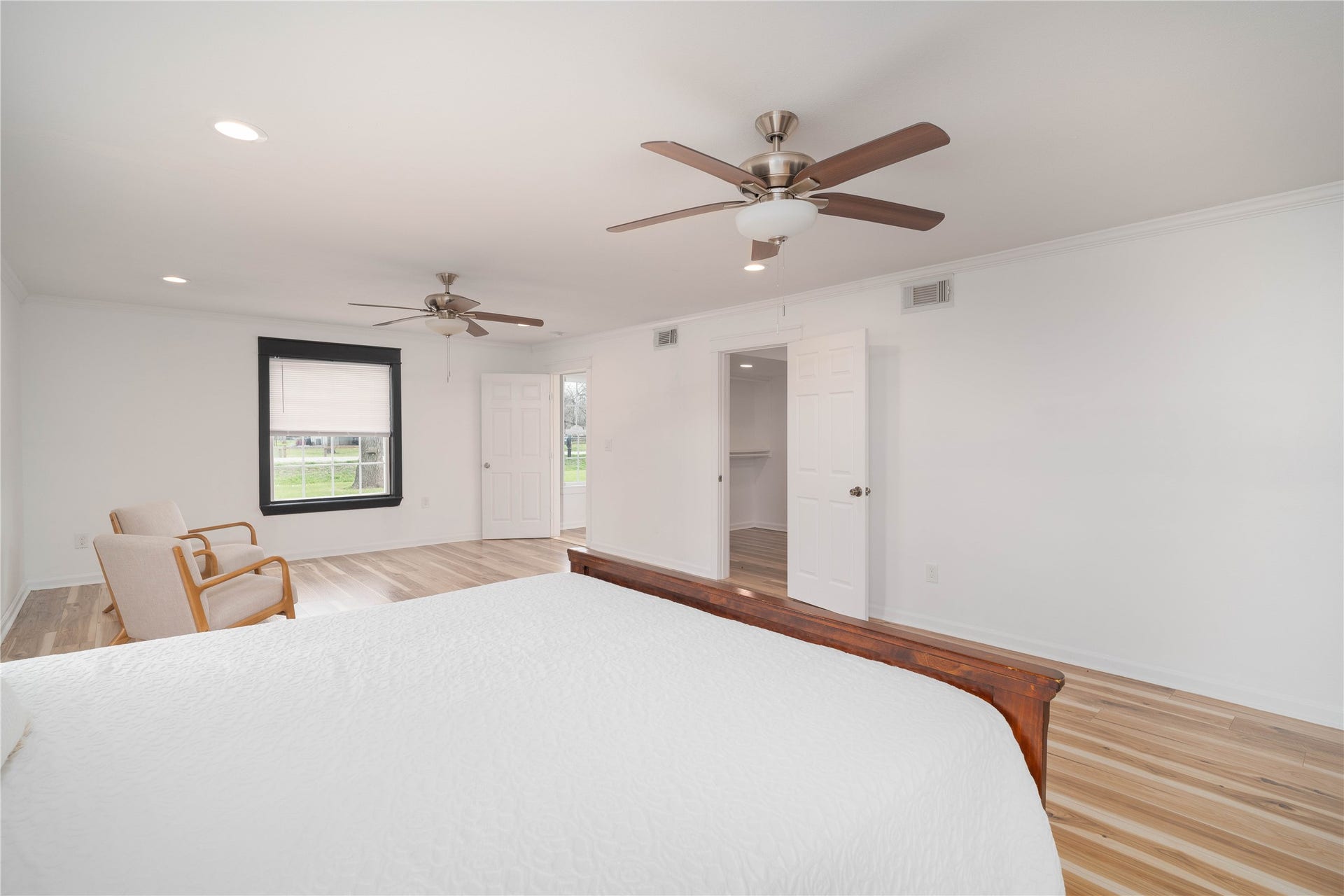 1635 Pony Lane, Wallis, TX 77485 Primary Bedroom Suite Expansive primary suite with large seating area, featuring wide plank flooring, recessed lighting, and dual ceiling fans for comfort. Large windows bring in natural light and views of the surrounding property.