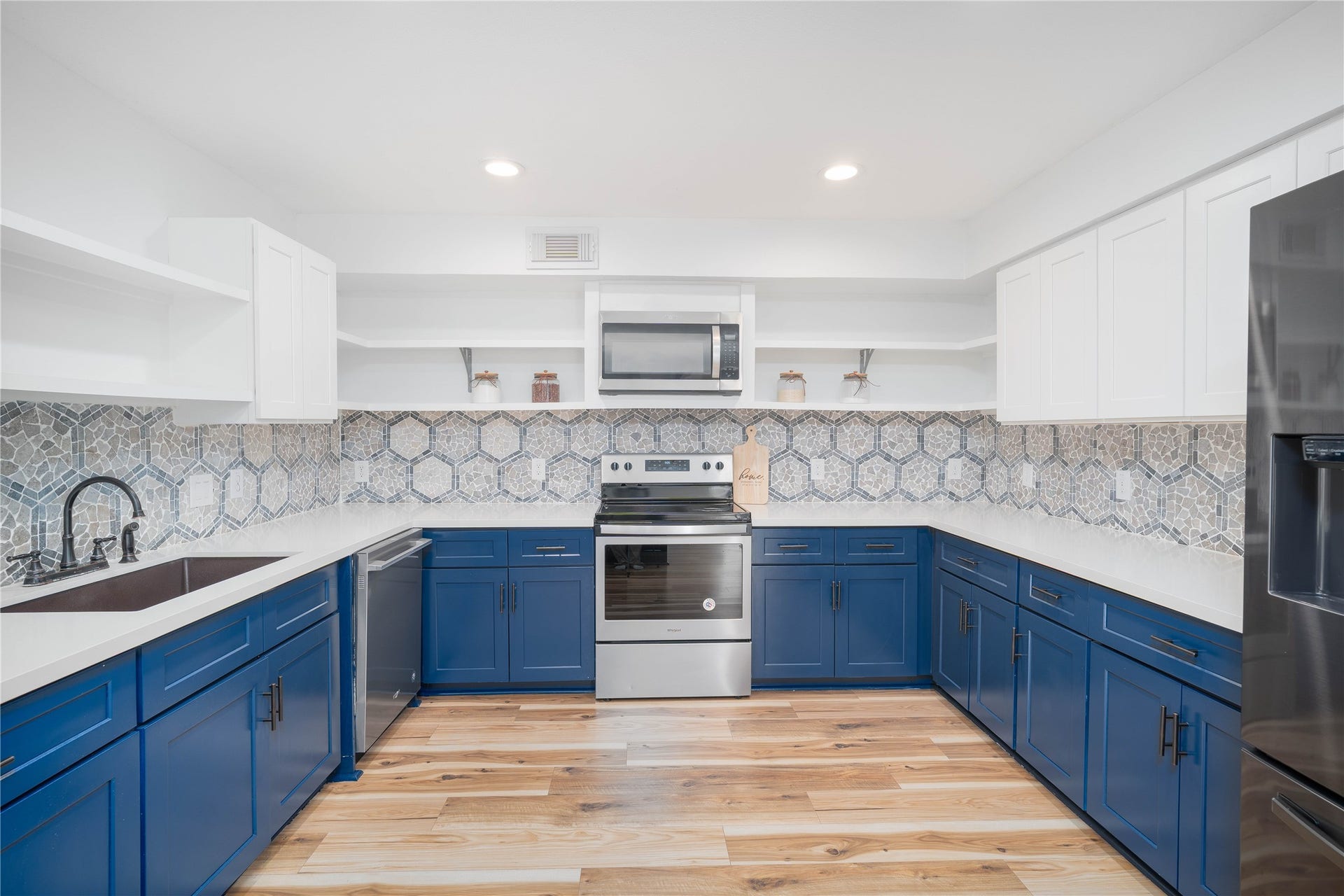 1635 Pony Lane, Wallis, TX 77485 Kitchen Stylish kitchen featuring blue shaker-style cabinetry, stainless steel appliances, quartz countertops, and a decorative tile backsplash.