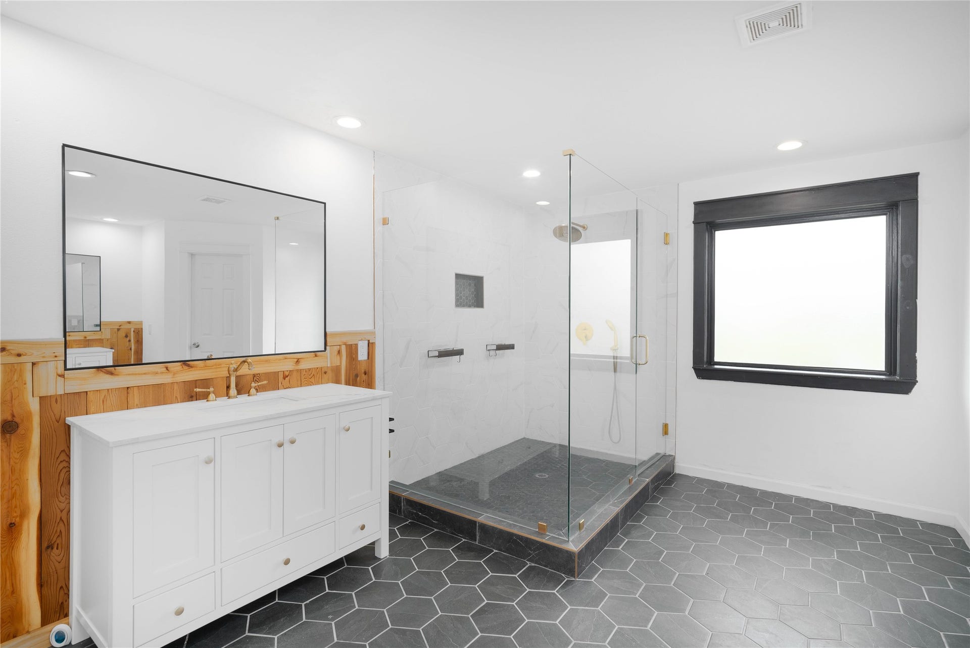 1635 Pony Lane, Wallis, TX 77485 Primary Bathroom Spa-inspired primary bath with hexagonal tile flooring, oversized frameless glass shower, and elegant gold-tone fixtures. A large vanity and mirror add both style and functionality (2nd vanity/mirror on opposite side).