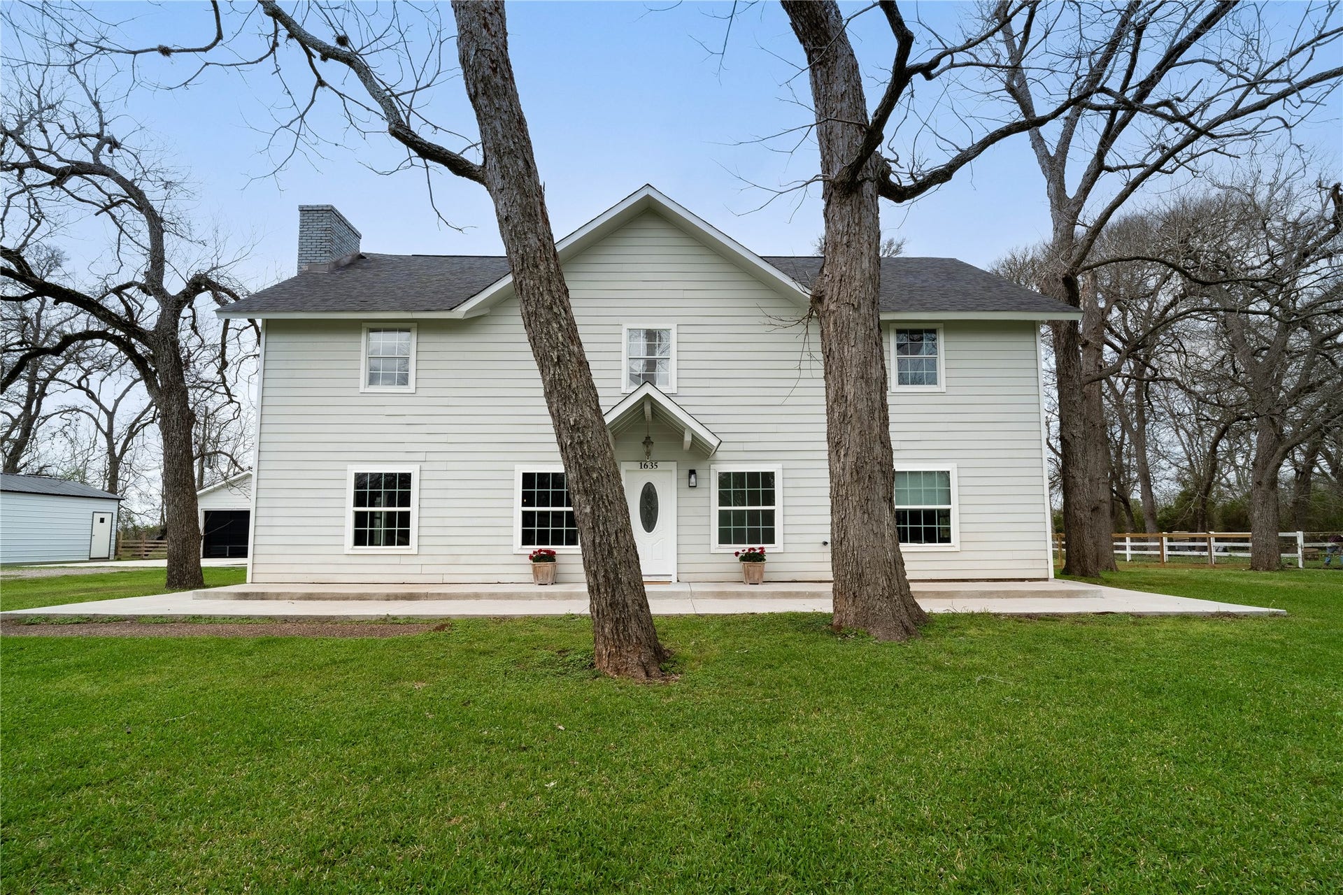 1635 Pony Lane, Wallis, TX 77485 Front Exterior Gorgeous farmhouse-style exterior with classic siding, welcoming front entry, and mature pecan trees framing the home.