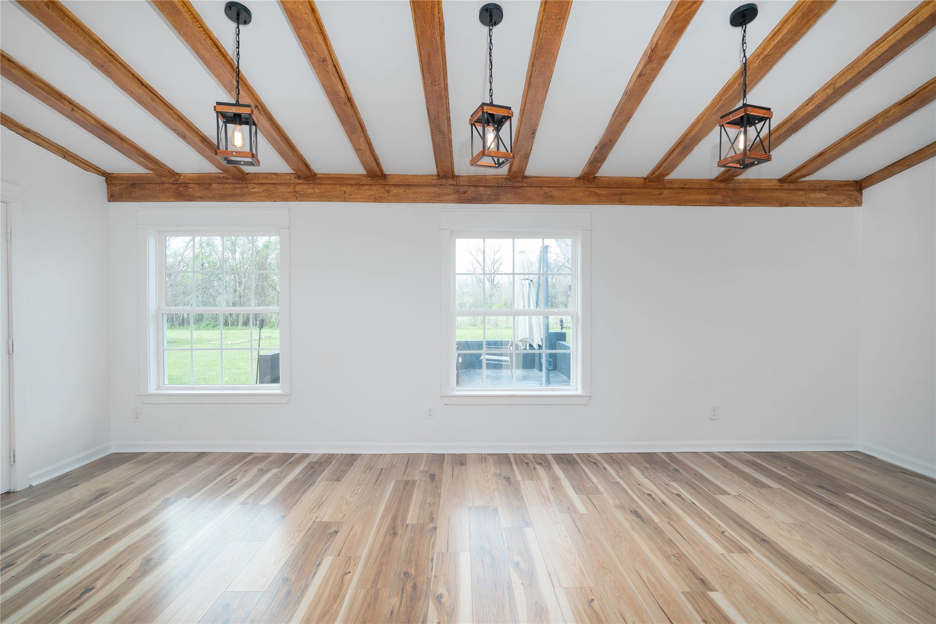 1635 Pony Lane, Wallis, TX 77485 Dining / Living Area Bright dining and gathering area with rustic beam accents and dual windows overlooking the back patio and property.