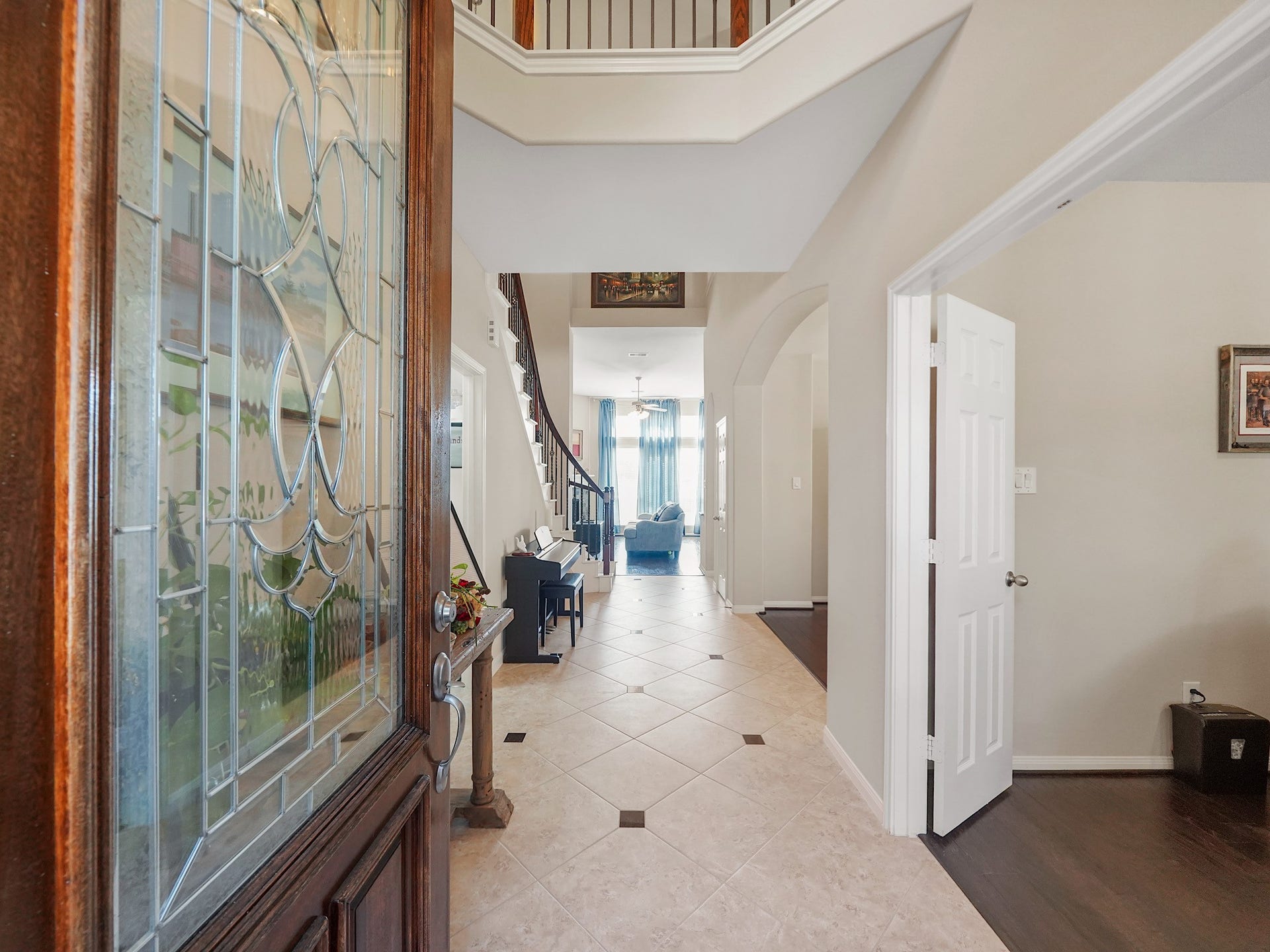 3250 Bandera Run Lane, Katy, TX 77494 Elegant entryway with a stunning glass-paneled door, leading to a spacious hallway with tile flooring, high ceilings, and a glimpse of the inviting living area beyond.
