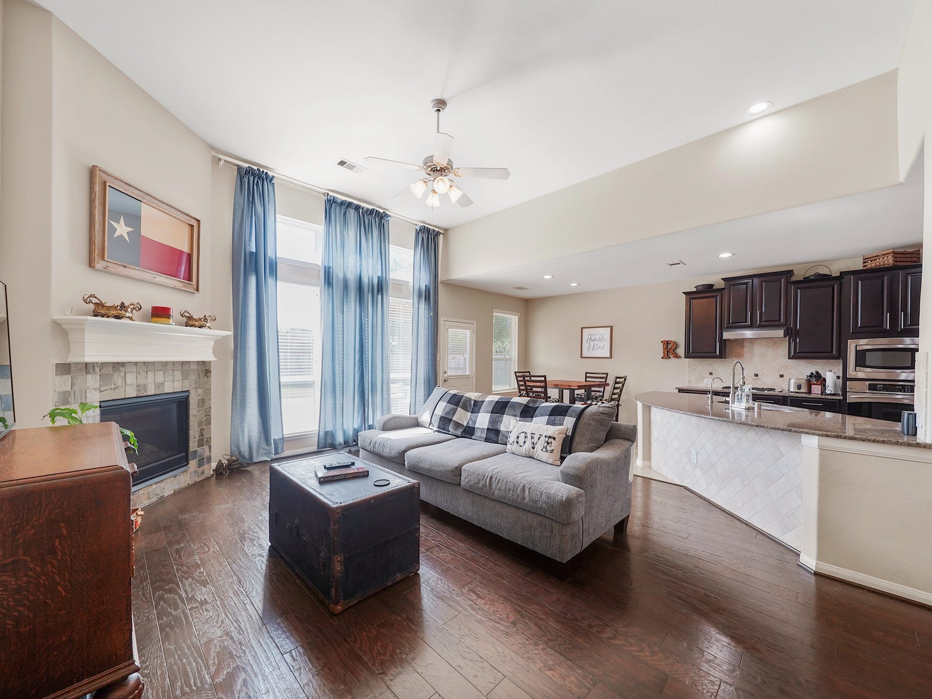 3250 Bandera Run Lane, Katy, TX 77494 Experience the inviting charm of a beautiful open living area, seamlessly connecting a cozy fireplace, modern kitchen, and ample natural light through elegant windows.