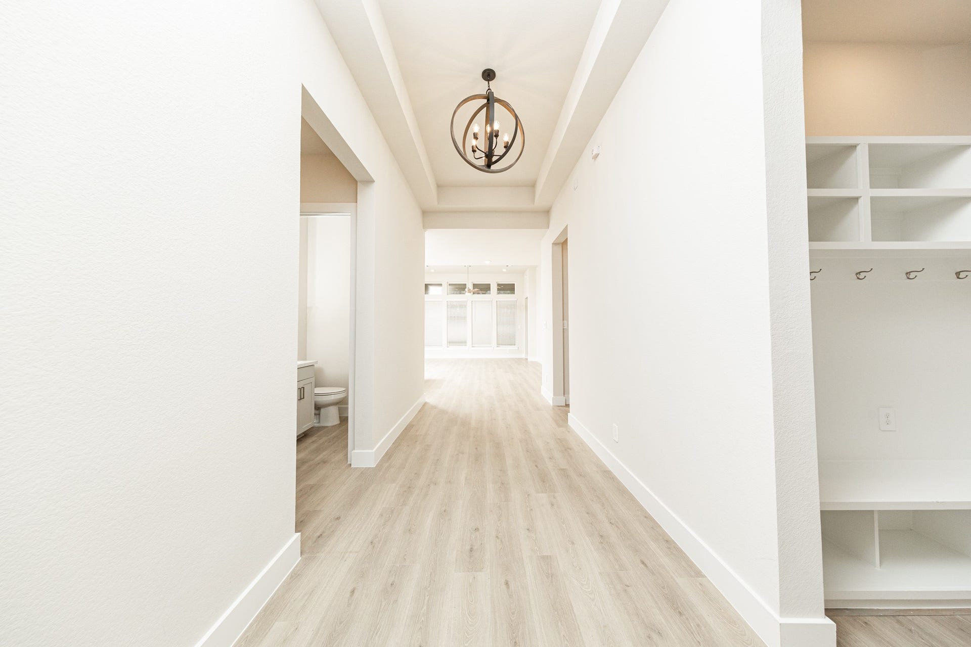 41422 Threadgill Way, Montgomery, TX 77316 A well appointed mud room on your right is an essential feature for a busy household. The space boasts custom-built white cabinetry and shelving, providing generous storage for coats, bags, and shoes. A comfortable built-in bench offers a convenient spot to sit, while three sleek hooks keep outerwear tidy and accessible.