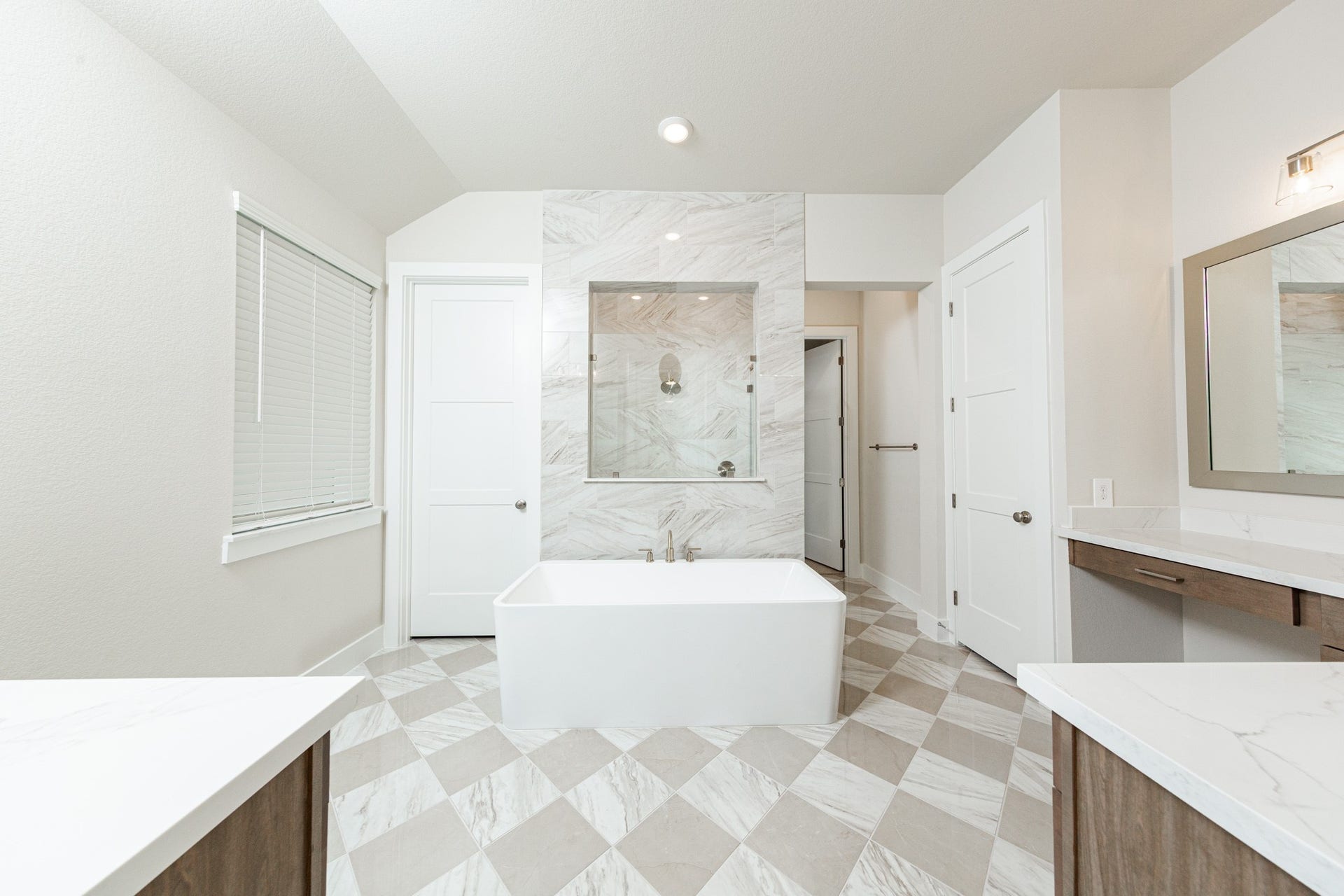 41422 Threadgill Way, Montgomery, TX 77316 The centerpiece of this contemporary primary bath is the deep, freestanding bathtub with gorgeous marble tile offering an ideal spot for relaxation with a unique view into the walk-in shower. The flooring features large square tiles set in a timeless diagonal, checkerboard pattern, adding visual interest and depth to the space.