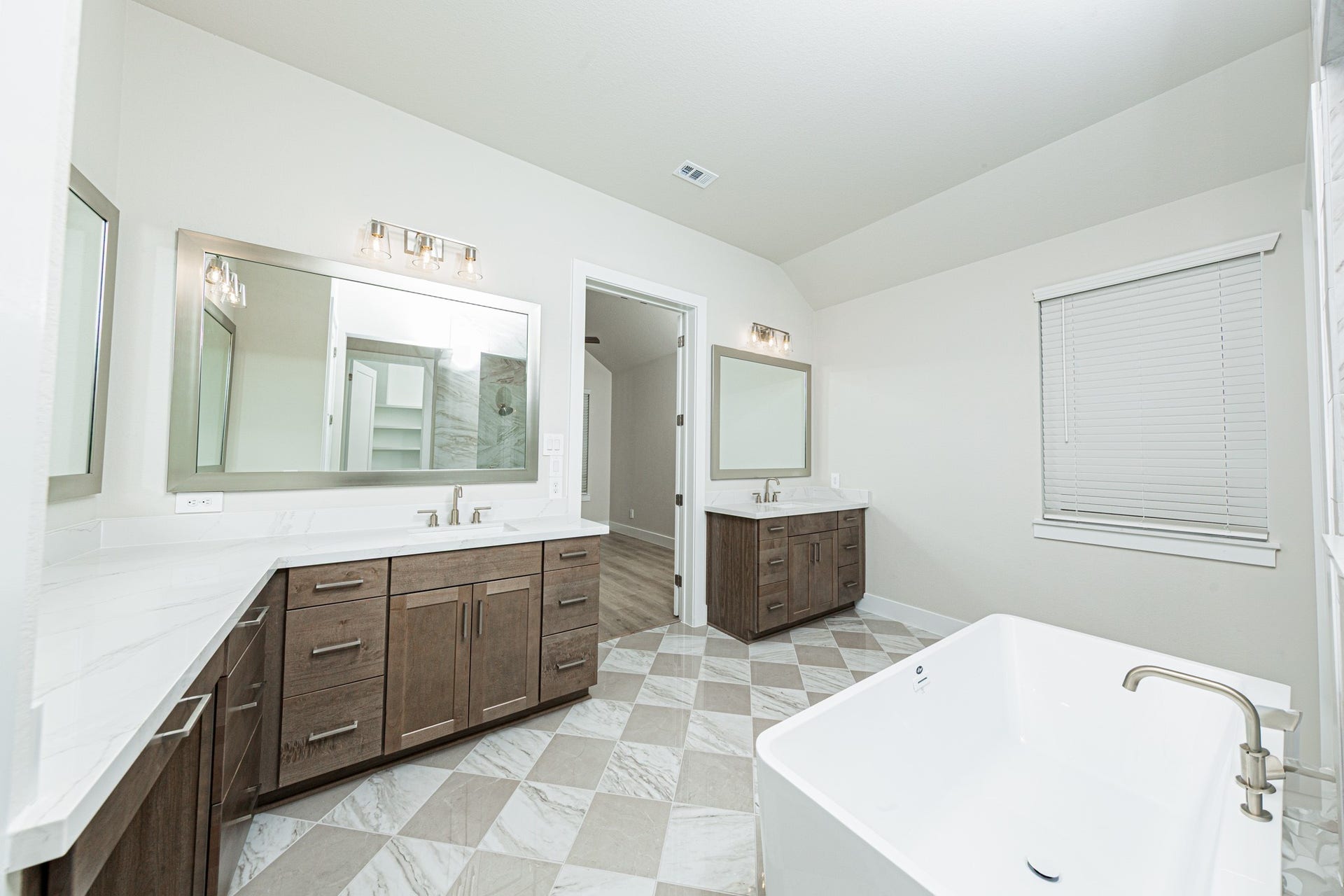 41422 Threadgill Way, Montgomery, TX 77316 Modern primary bath features dual vanities with sleek white cabinetry, a quartz countertop, framed vanity mirrors, and brushed nickel fixtures for a truly contemporary feel.