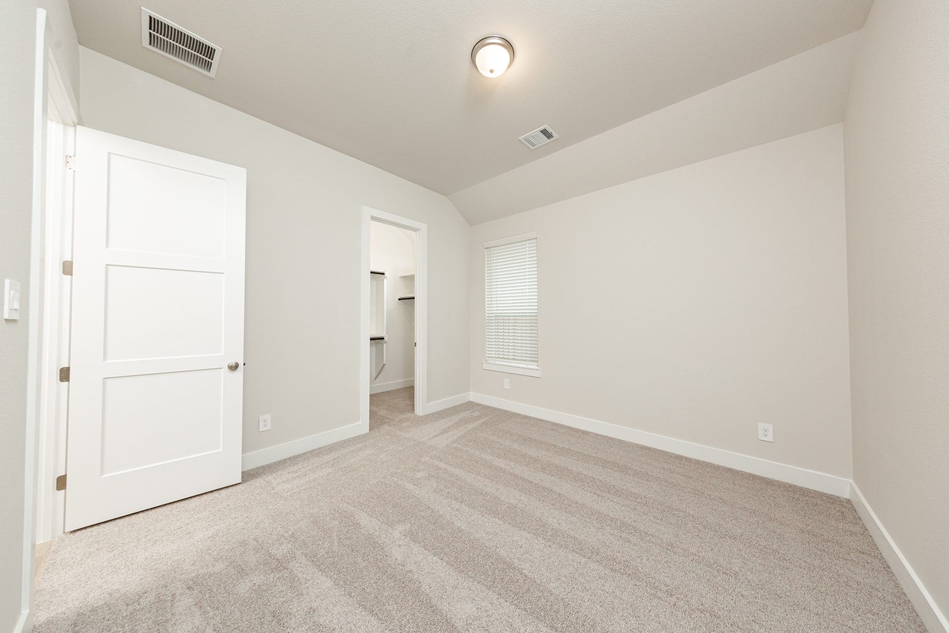 41422 Threadgill Way, Montgomery, TX 77316 This inviting secondary bedroom combines comfort and modern elegance, featuring sloped ceiling, plush carpeting, a neutral color palette, abundant natural light streaming through a large window, and a walk-in closet.