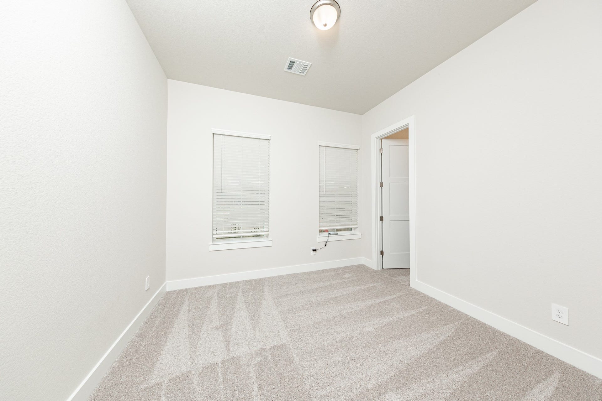 41422 Threadgill Way, Montgomery, TX 77316 Tucked peacefully in the front of the home is this secondary bedroom. It features a sloped ceiling, plush carpet flooring, large windows with fitted blinds, and a walk-in closet.