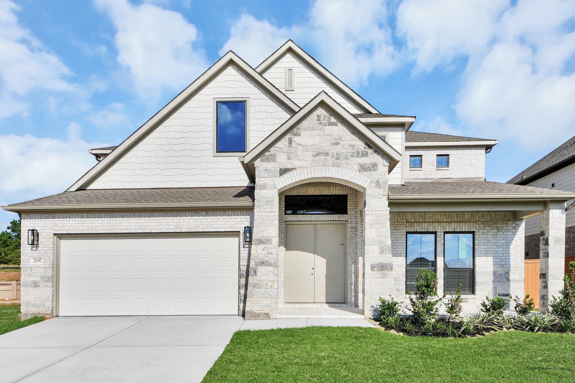 2097 Corn Thistle Way, Magnolia, TX 77355 Meticulously maintained yard and lush landscape, paired with a premium elevation featuring captivating brick accents. Modern coach lights add a touch of contemporary elegance to the exterior.