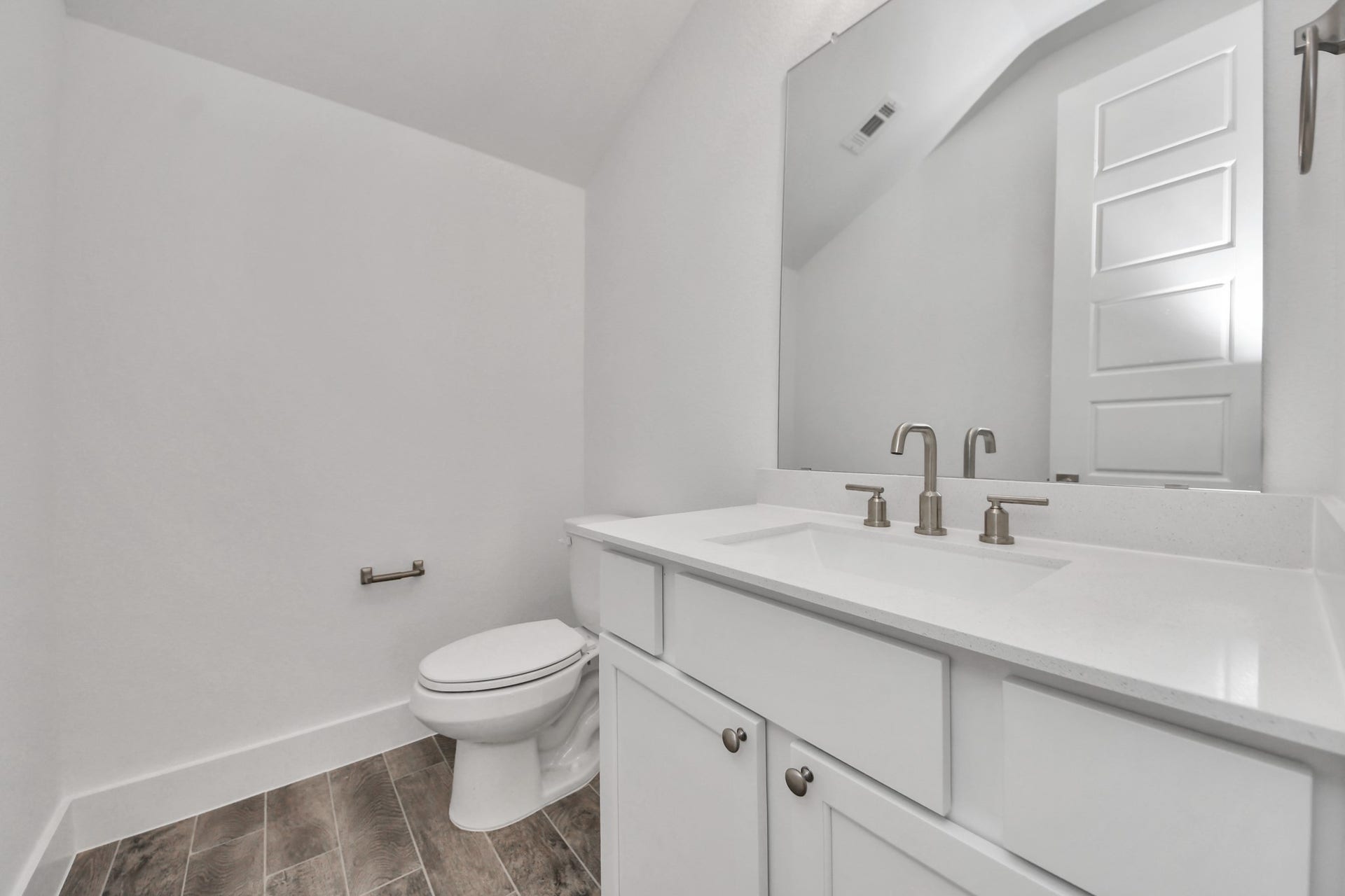 2097 Corn Thistle Way, Magnolia, TX 77355 Sophisticated half bathroom adorned with contemporary finishes. The elegant 5-panel door welcomes you to a space where style meets functionality. Notice the sleek hardware accents that add a touch of modern charm. The vanity boasts light-colored countertops, beautifully complemented by a tasteful vanity light, creating a well-lit and inviting atmosphere.