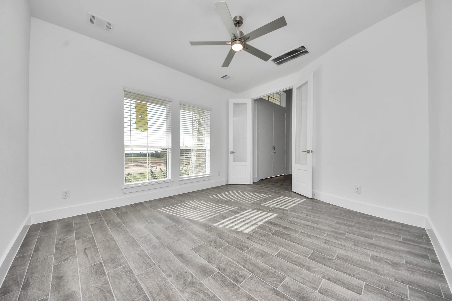 2097 Corn Thistle Way, Magnolia, TX 77355 Experience the perfect blend of sophistication and warmth in this home office, boasting elegant wood-look tile flooring and flooded with natural light from expansive windows and French doors.