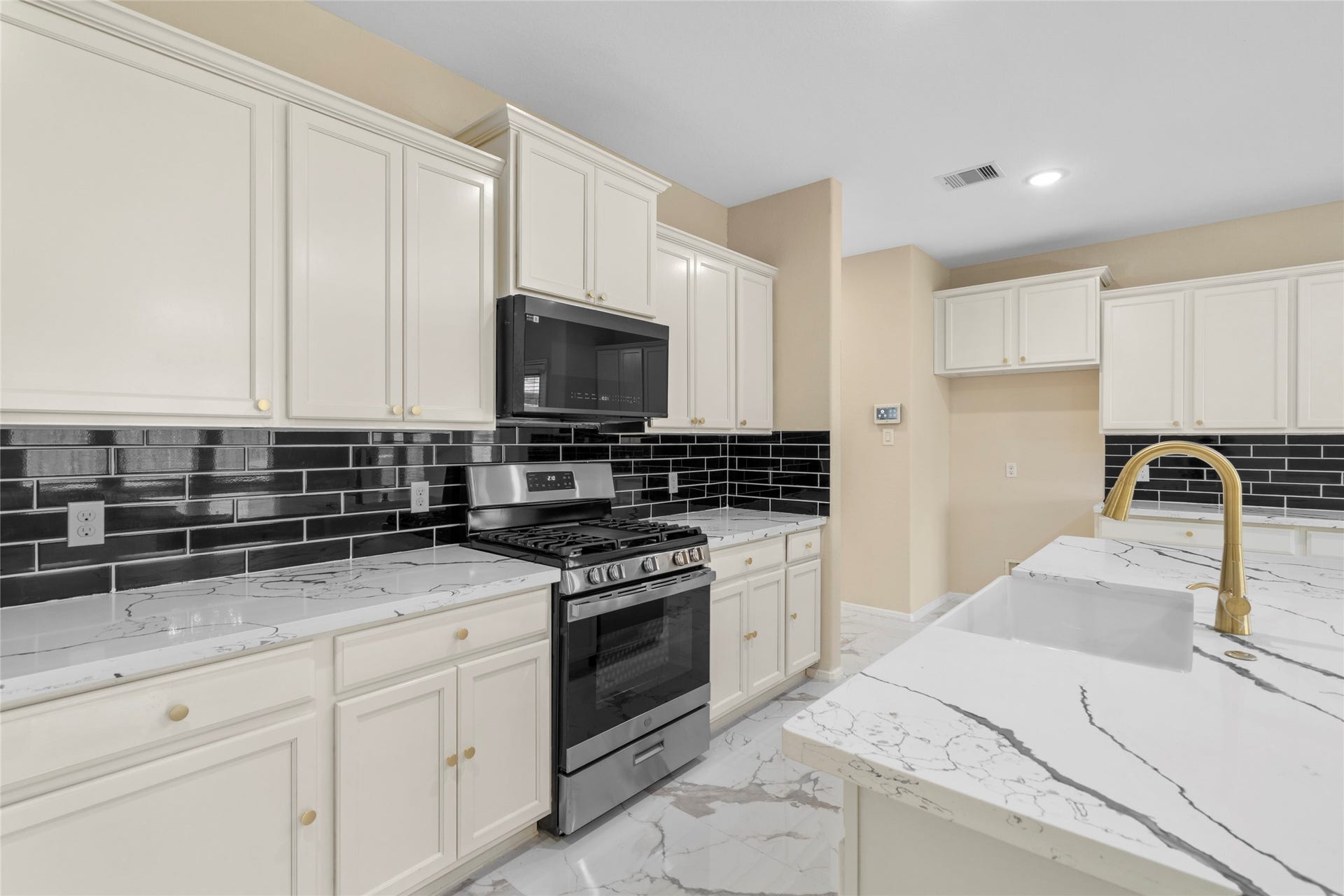 9423 Mineral Rock Lane, Richmond, TX 77407 Experience culinary delight in this sleek kitchen featuring modern black tile backsplash, elegant marble countertops, and top-of-the-line stainless steel appliances.