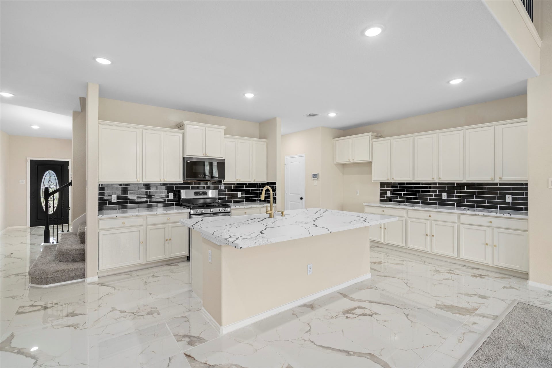 9423 Mineral Rock Lane, Richmond, TX 77407 Experience culinary elegance in this spacious kitchen, featuring sleek tile flooring, pristine cabinetry, and a striking black tile backsplash that complements the modern island centerpiece.