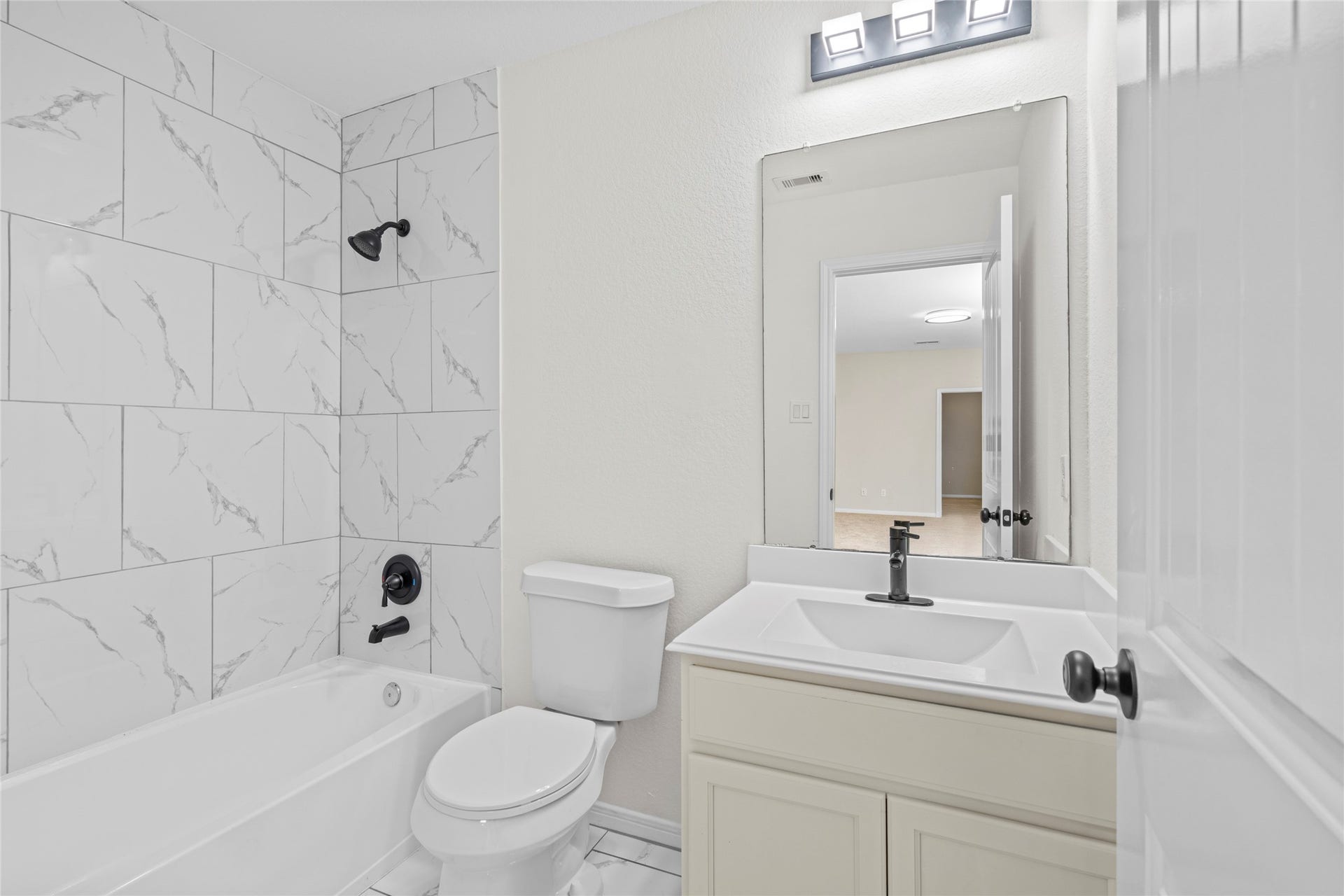 9423 Mineral Rock Lane, Richmond, TX 77407 Stylish bathroom featuring a modern vanity, sleek fixtures, and elegant marble tile in the bathtub area.